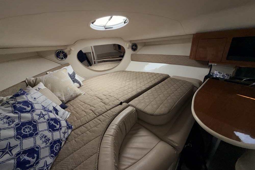 Luxurious interior of a 2001 Monterey 282 Cruiser with cozy bedding and elegant wood finishes.