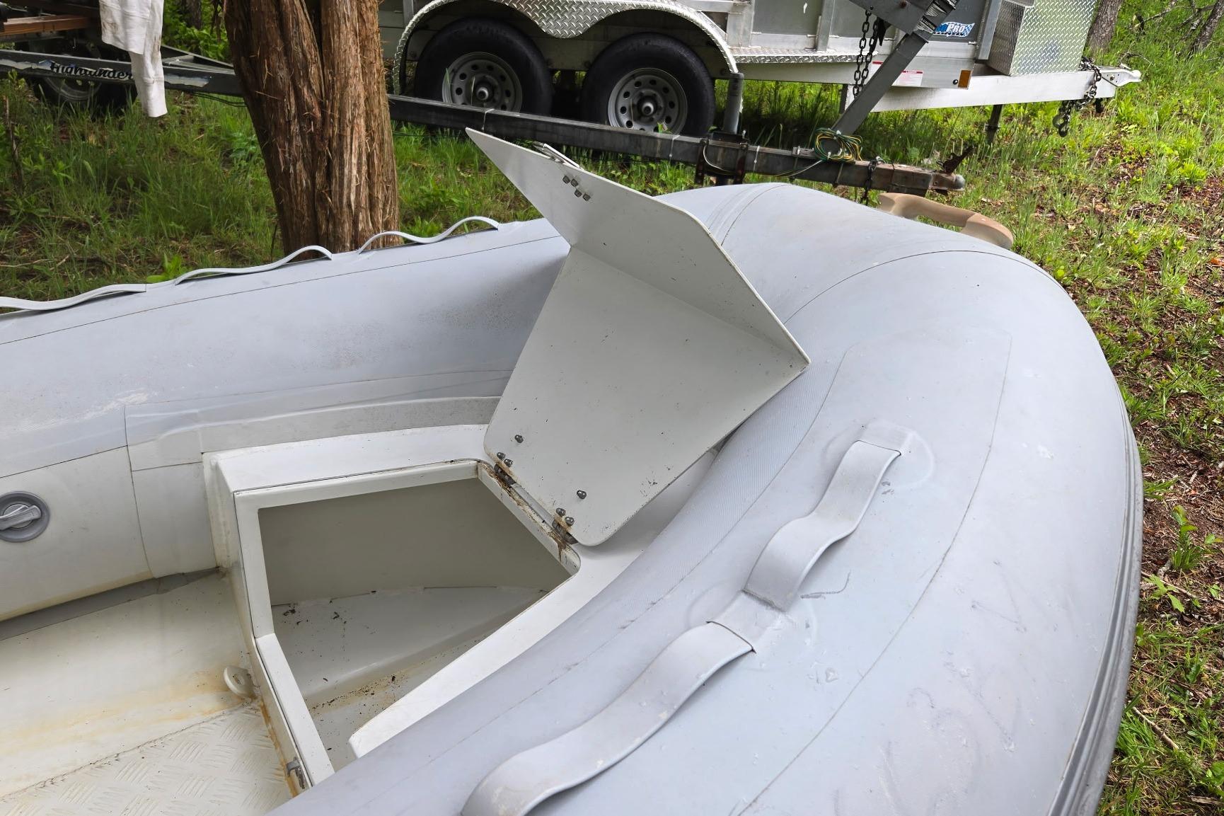 Inflatable boat with open storage compartment, near a trailer, Marine Trader 36, 1987 model.