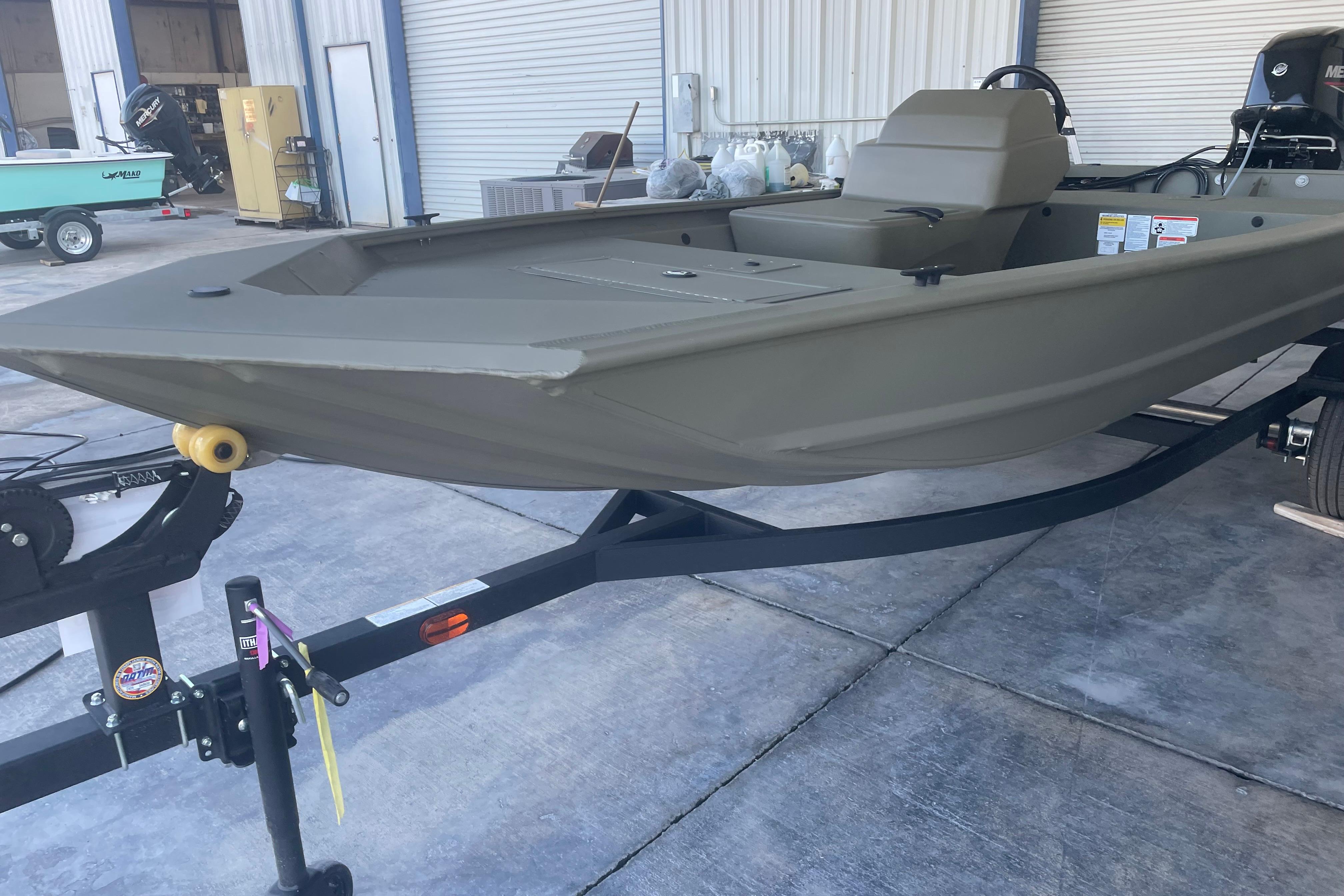 2026 Tracker Grizzly 1648 SC boat on trailer, parked outside a warehouse.