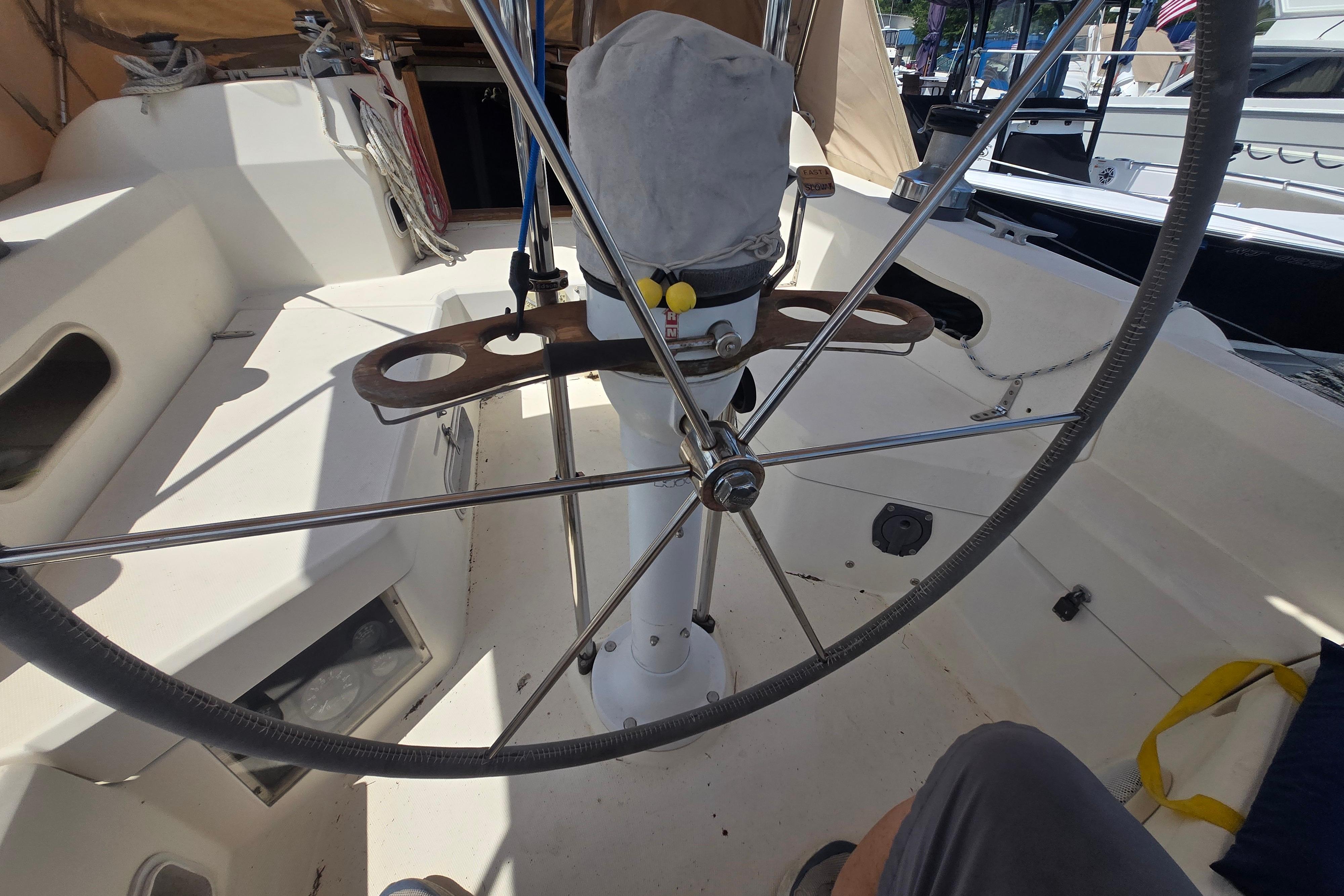 Cockpit of a 1988 Sabre 38 sailboat with a large steering wheel and covered instruments.
