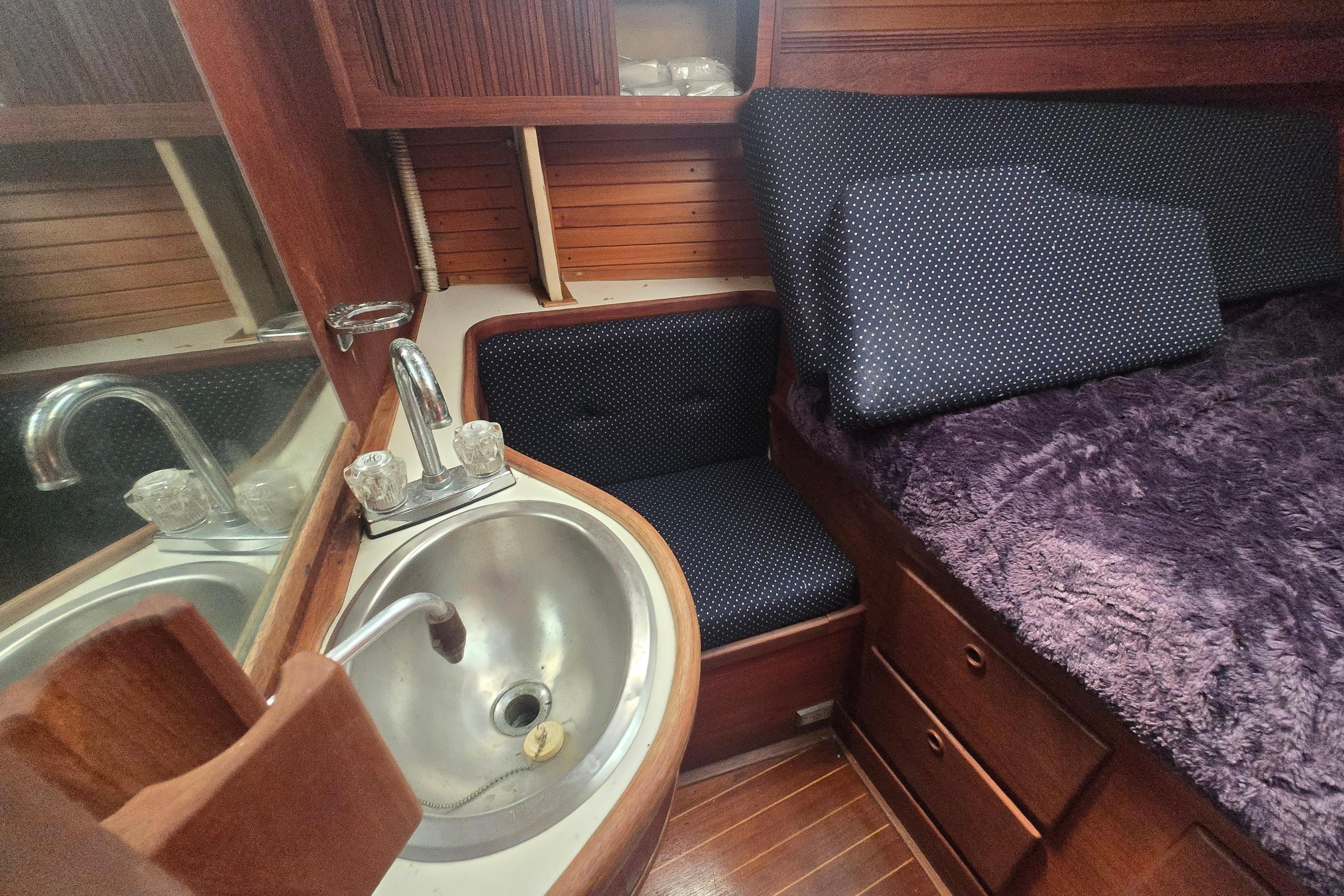 Cozy cabin interior of 1988 Sabre 38 sailboat with sink and plush bedding.