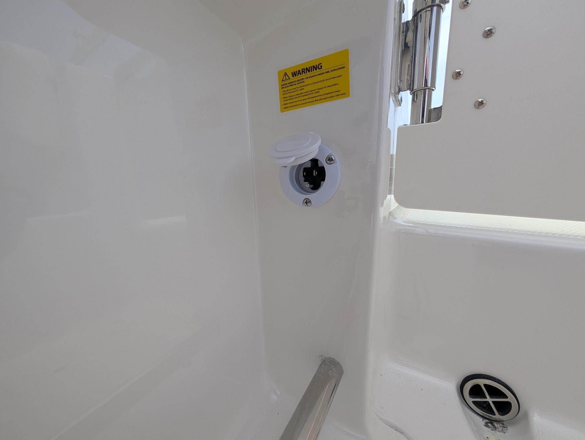 2025 Robalo R222 Explorer boat interior detail with warning label and power socket.