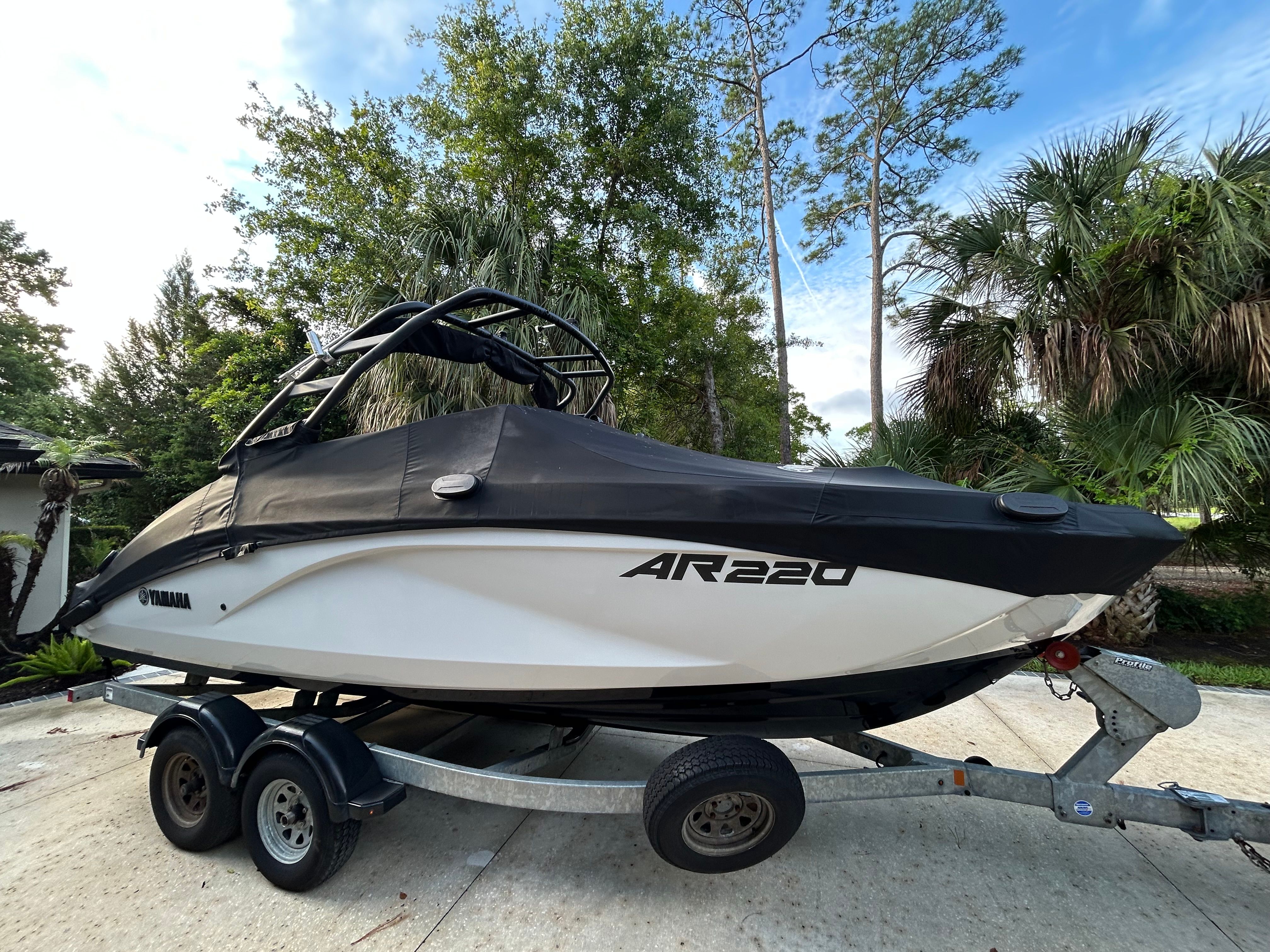 A Yamaha AR220 boat on a trailer, surrounded by trees.
