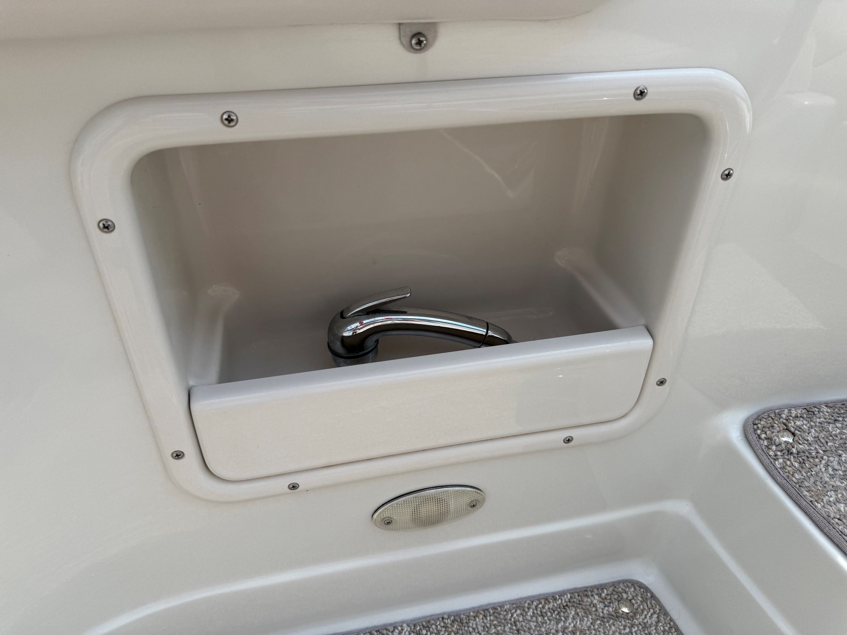 A built-in faucet in a white compartment on a boat.