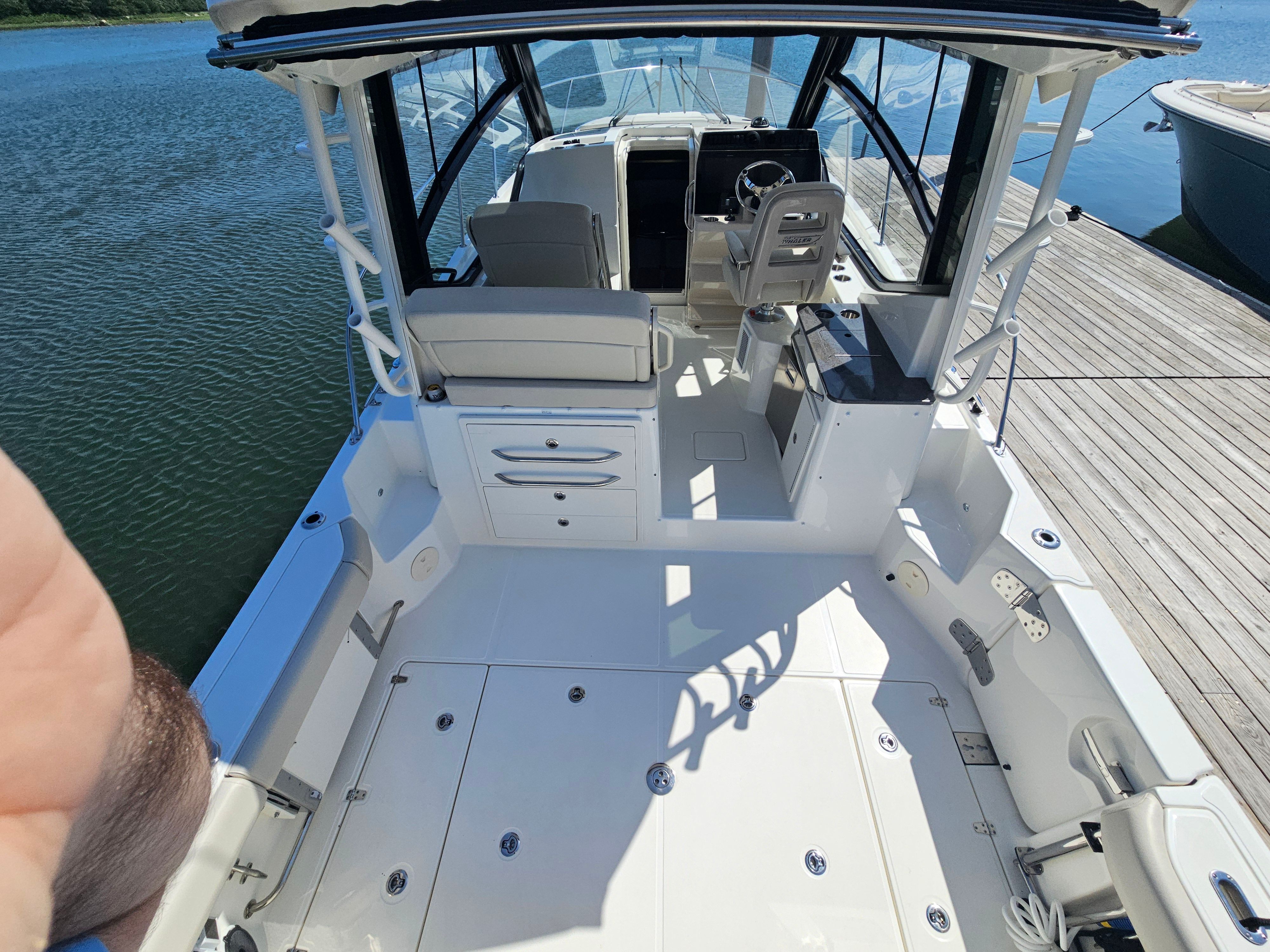 The image shows the cockpit of a Boston Whaler 325 Conquest docked at a pier.