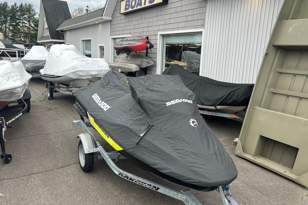 2014 Sea-Doo Wake Pro 215 jet ski covered, parked outside a boat dealership.