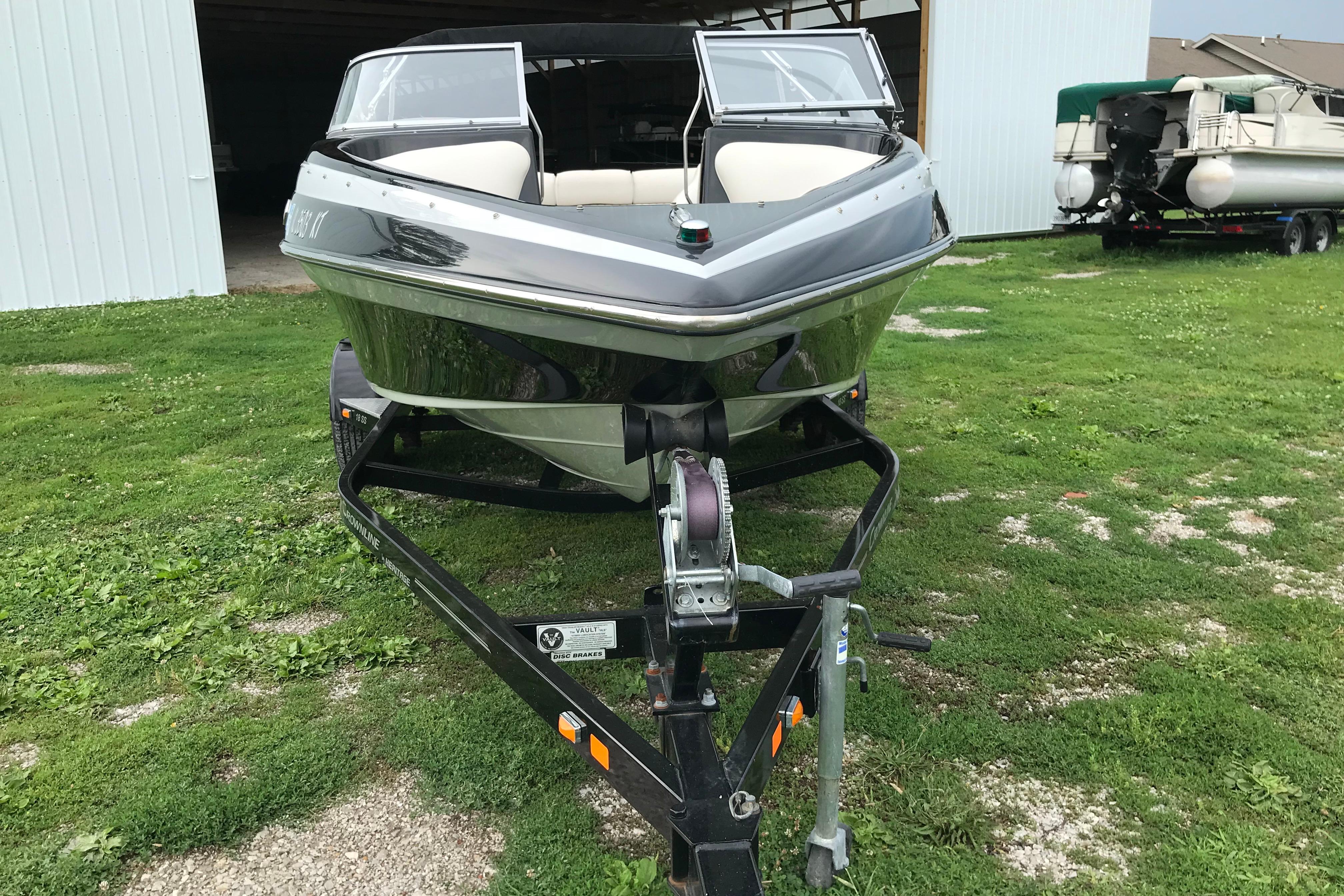 2015 Crownline 18 SS boat on trailer, parked on grass near a storage building.