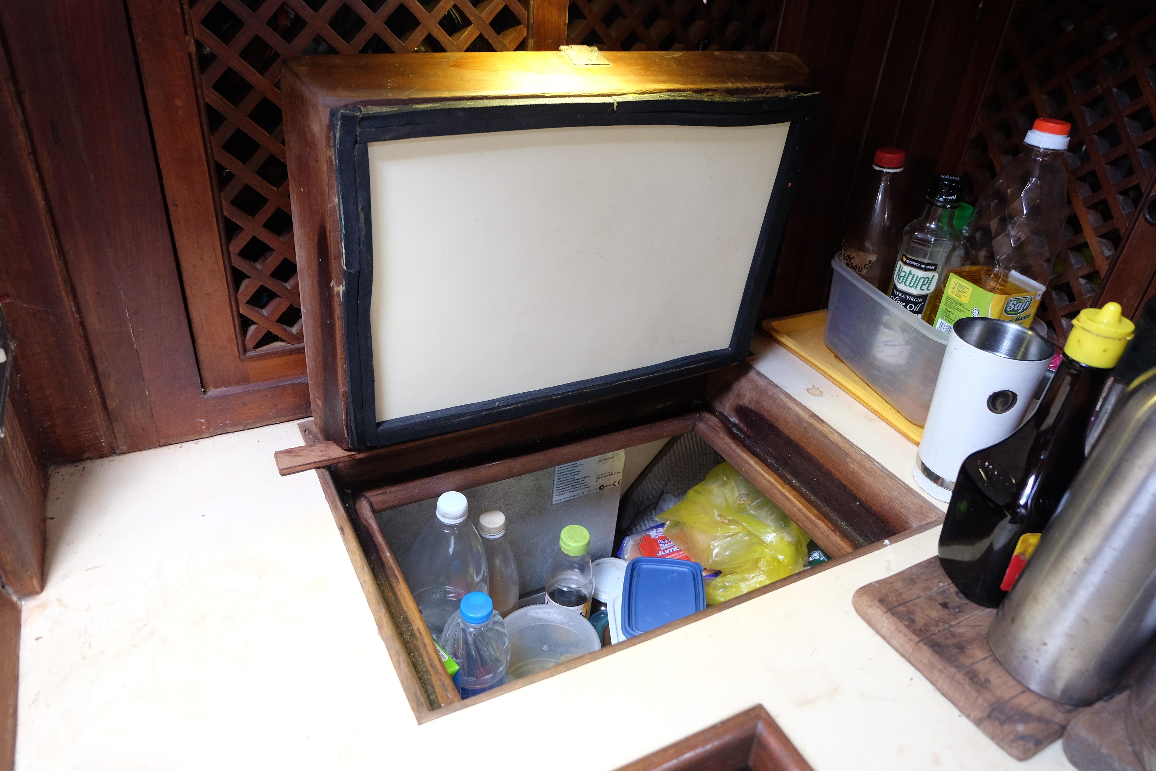 Interior of a 1979 Westwind 35 boat with open storage compartment and various bottles.