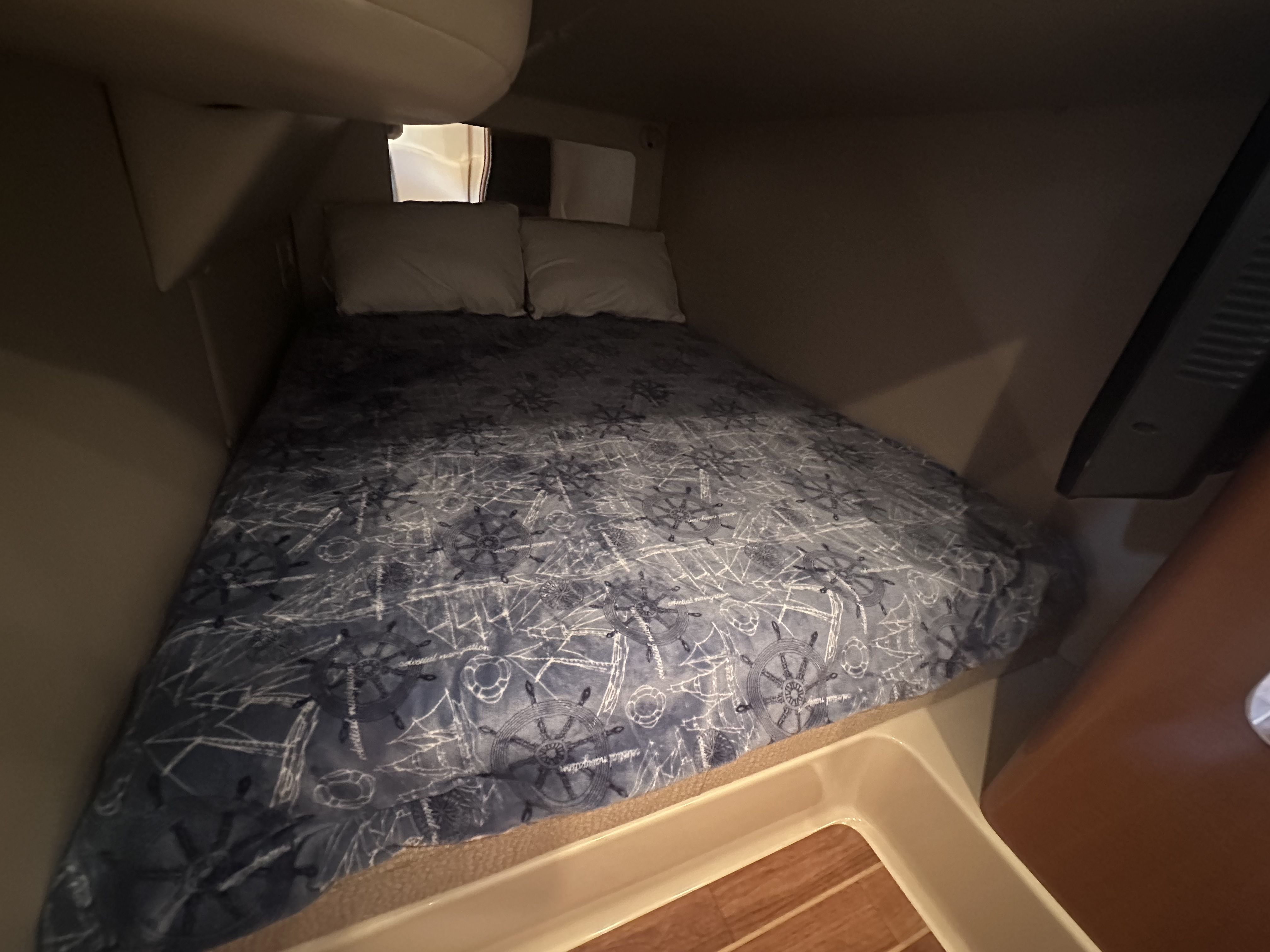 Cabin with double bed and blue bedspread, wooden floor, and soft pillows.