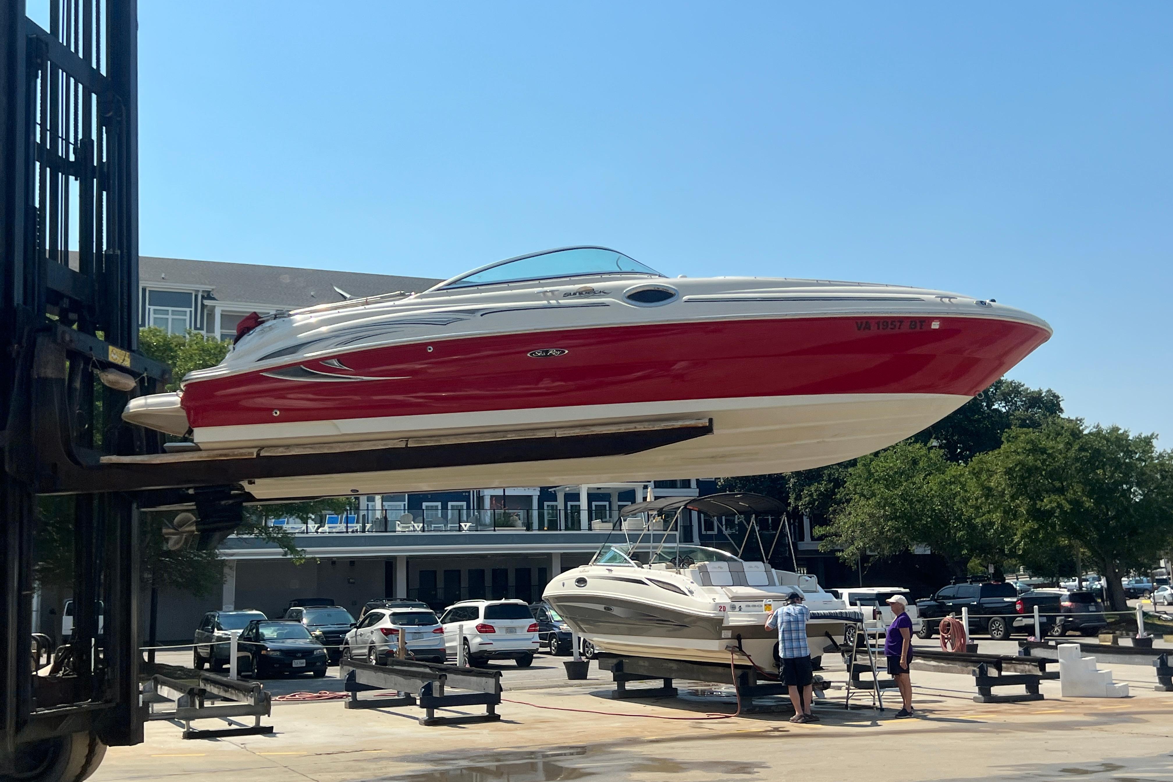 2005 Sea Ray 240 Sundeck boat lifted by forklift at marina, sunny day.