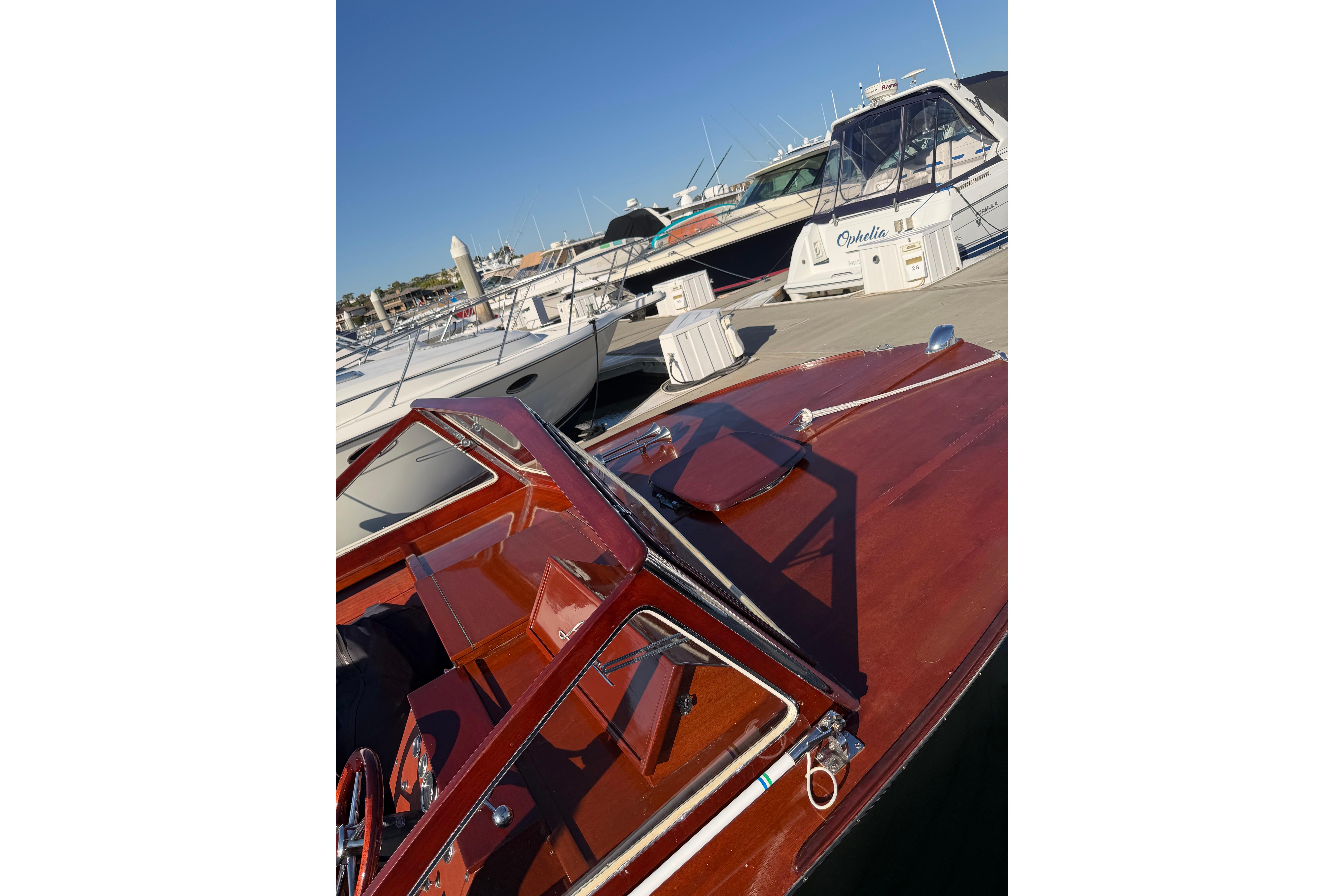1964 Lyman 25 Sleeper boat docked at marina under clear blue sky.