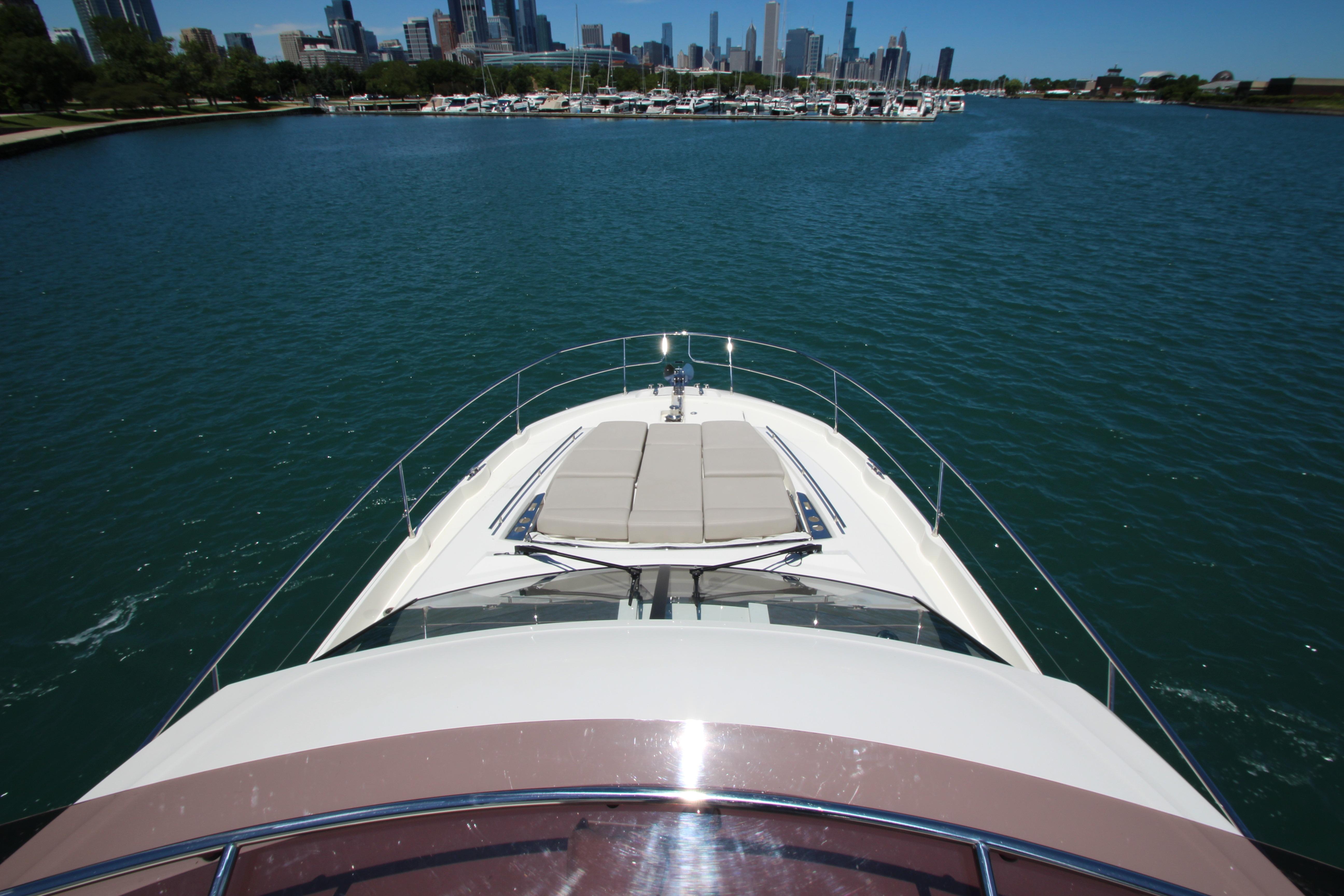 2022 Prestige 520 yacht cruising on a serene lake with city skyline in background.