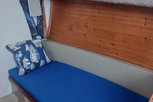 Interior of 1989 O'Day 272 sailboat with blue cushion and nautical-themed pillow.