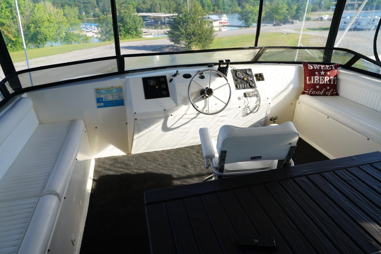 Cockpit of 2000 Stardust Cruisers 83'x17' houseboat with steering wheel and seating.