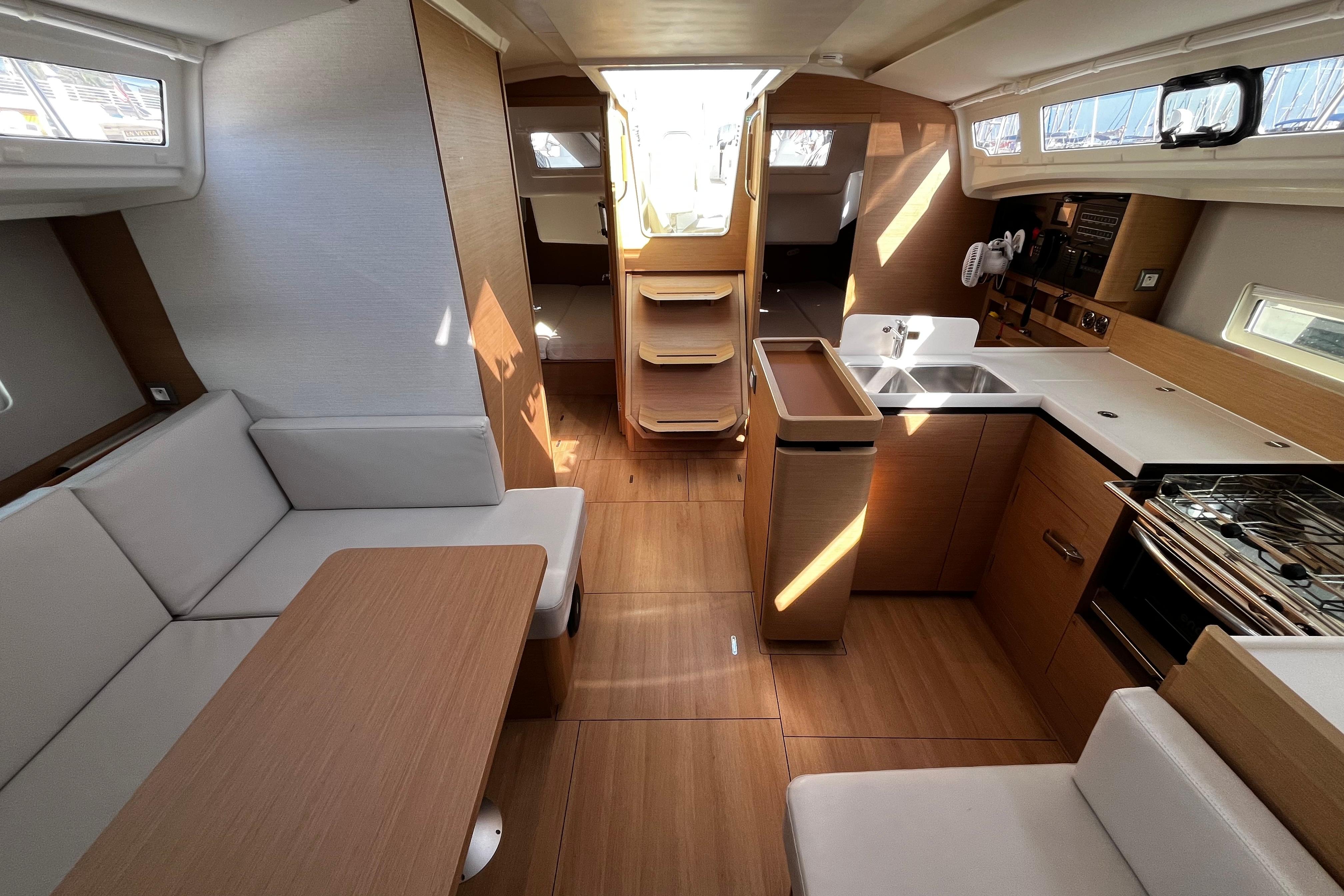 Interior of 2024 Jeanneau Sun Odyssey 410 yacht, featuring modern kitchen and seating area.