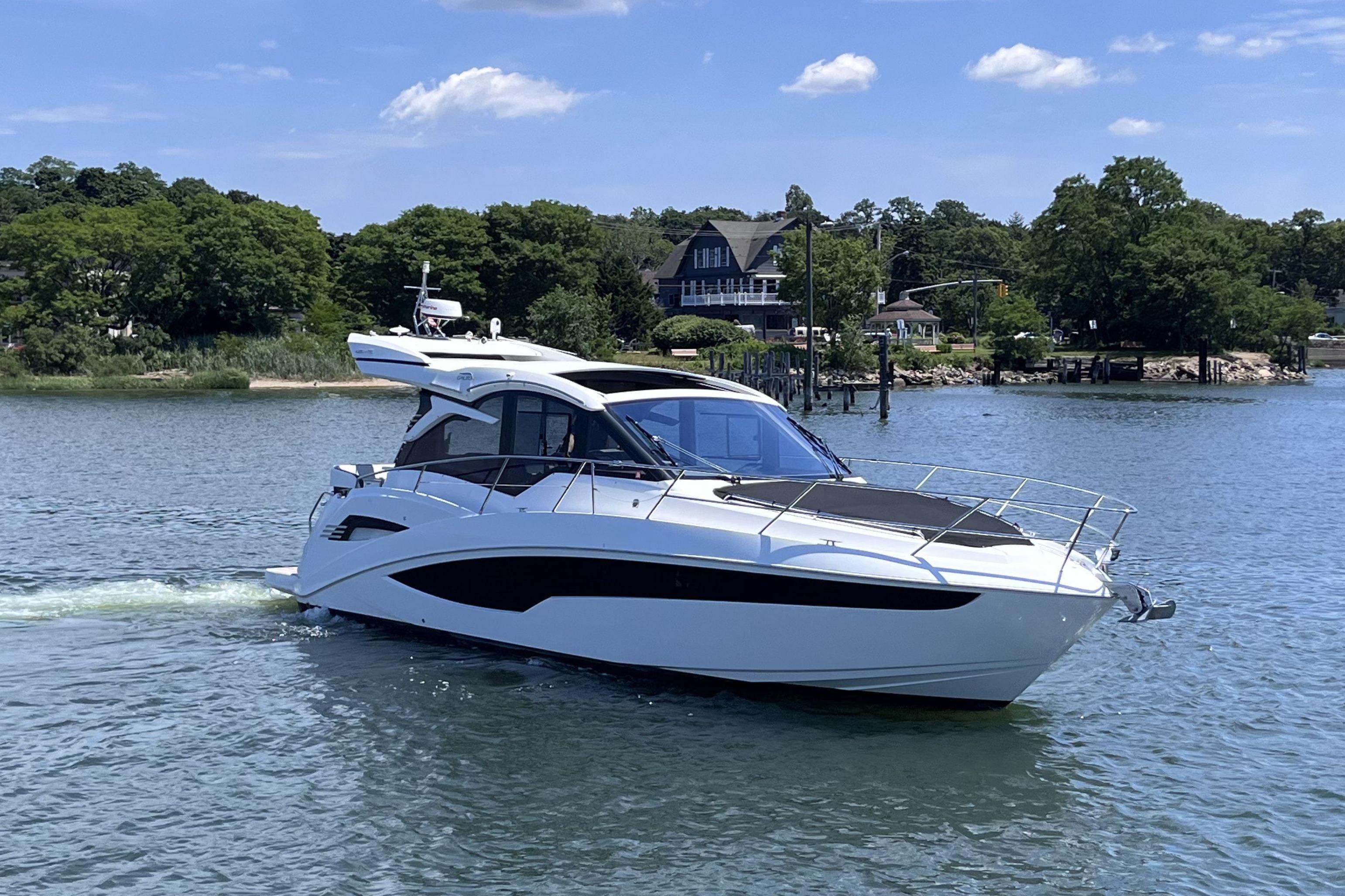 2024 Galeon 425 HTS yacht cruising on a serene lake with lush greenery.