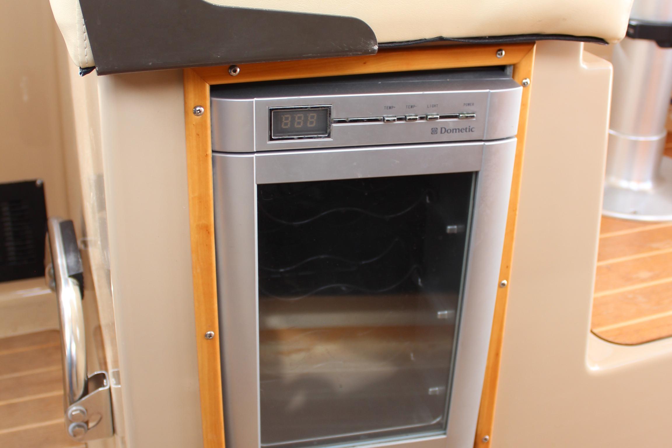 Dometic fridge inside 2013 Cutwater 28 LE boat, featuring digital display and wooden trim.