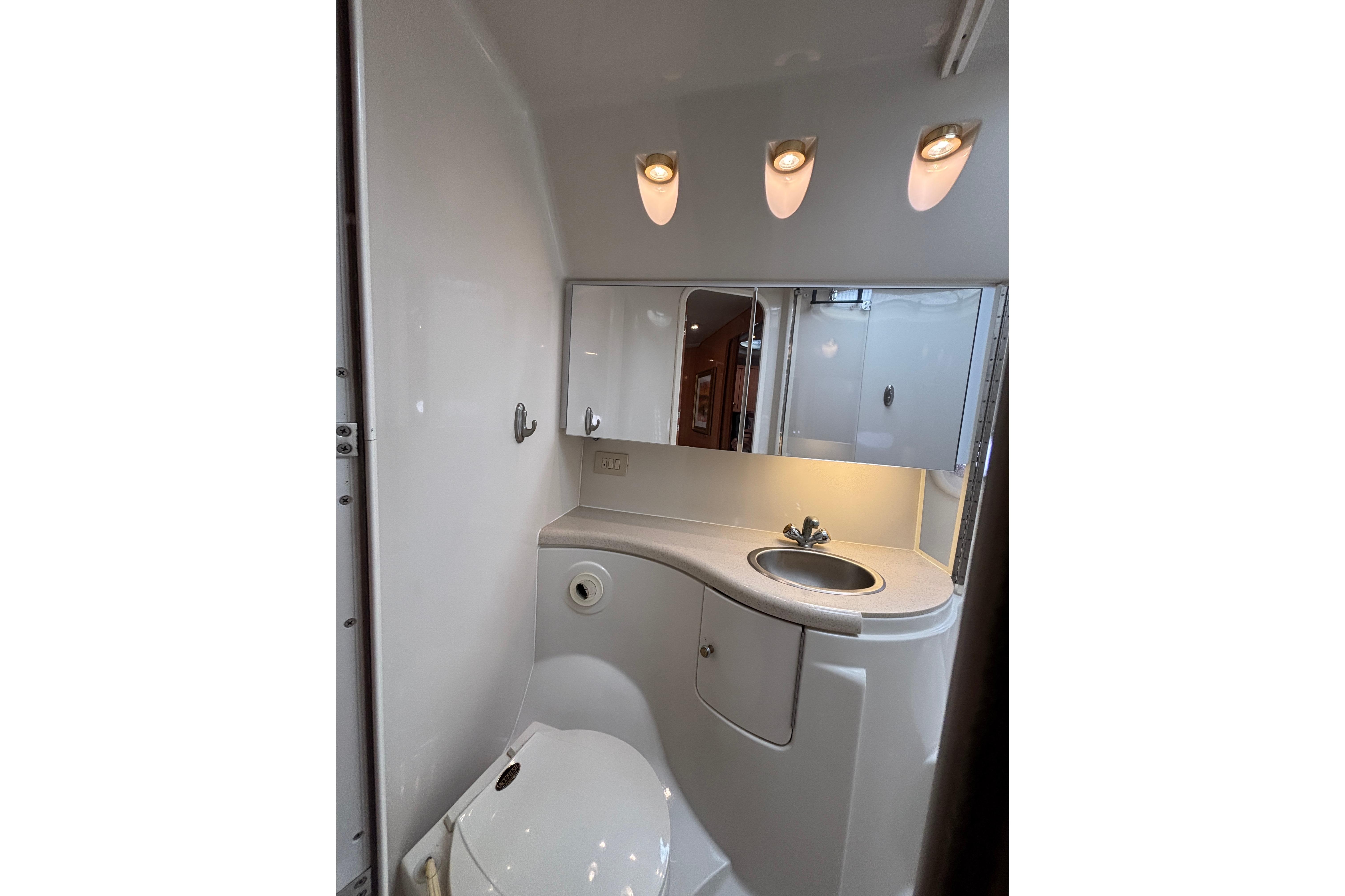 Compact bathroom in 2000 Regal Commodore 4160 yacht with sink, toilet, and mirror lighting.