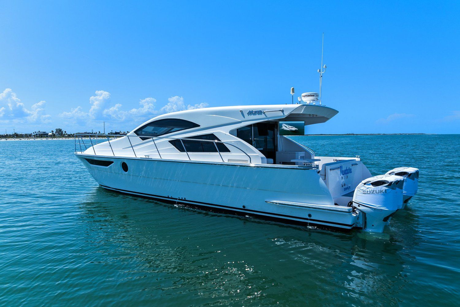 A white catamaran with two outboard motors on calm water under a blue sky.