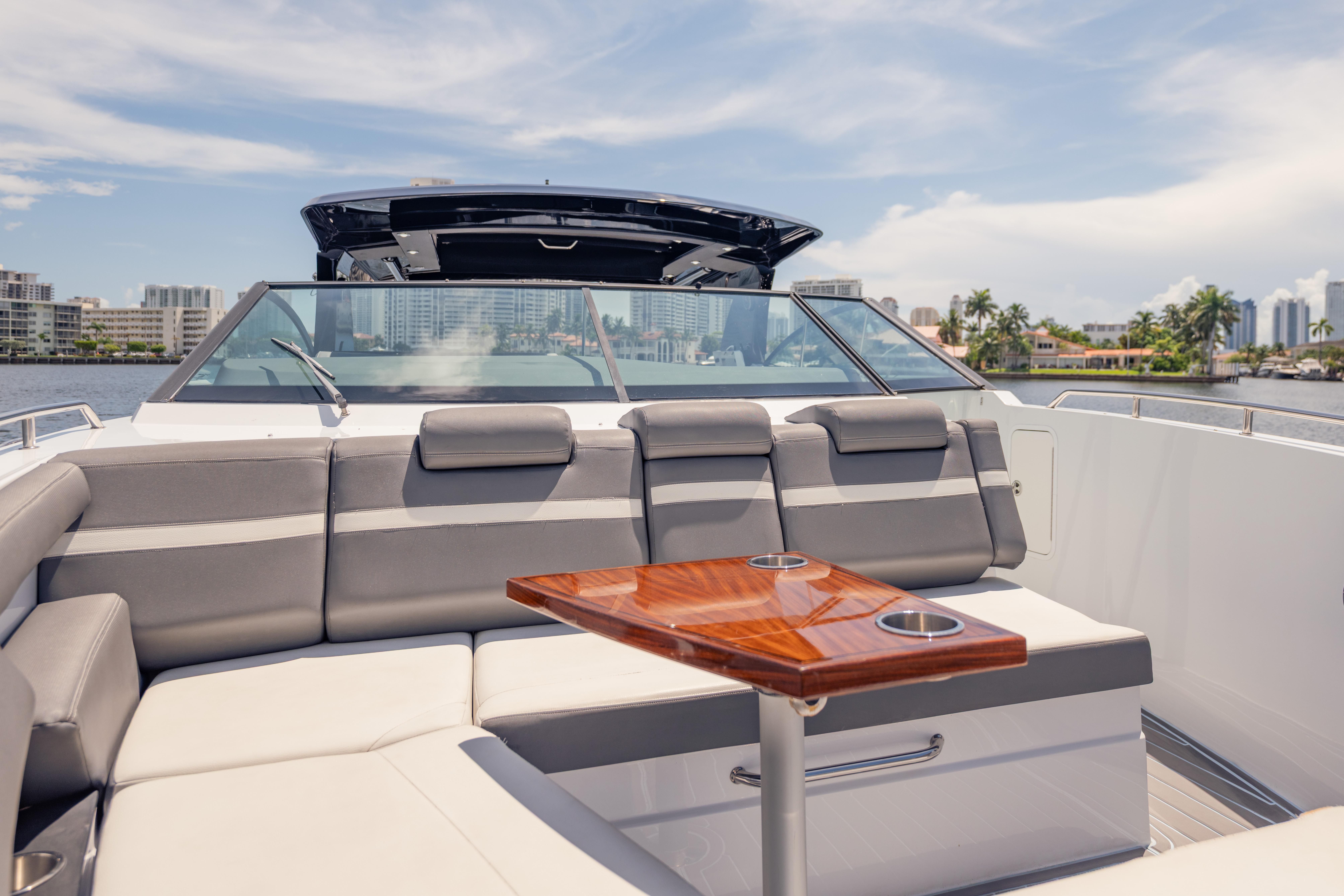 2021 Cruisers Yachts 38 GLS interior with luxurious seating and wooden table, cityscape in background.