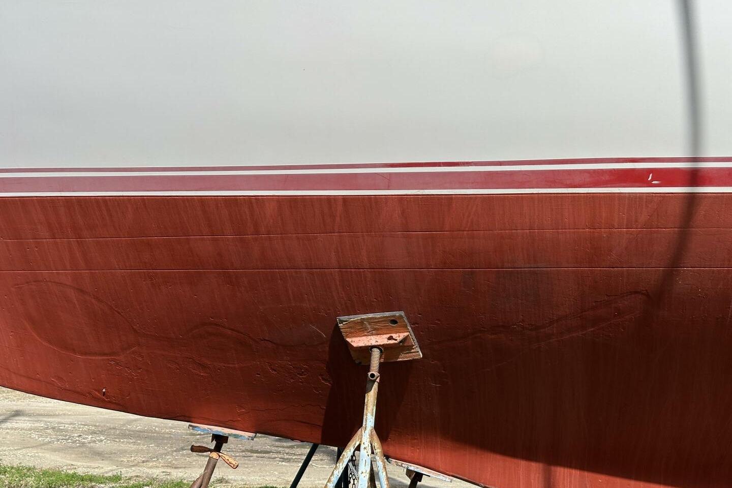Red and white hull of a 1986 Pan-Oceanic 46 boat on a stand.