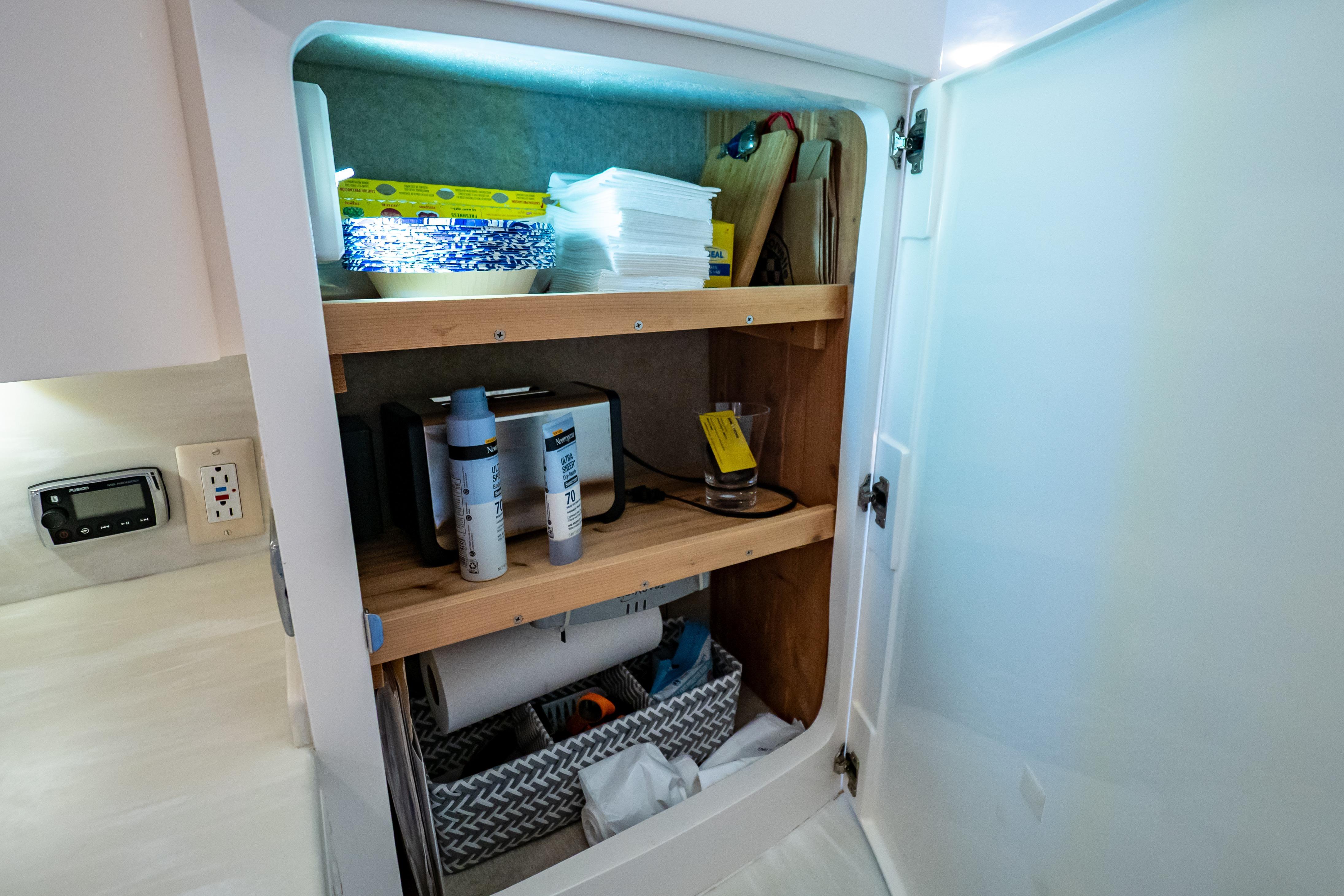 Cabinet storage inside a 2016 Intrepid 400 Cuddy boat, featuring shelves with various items.