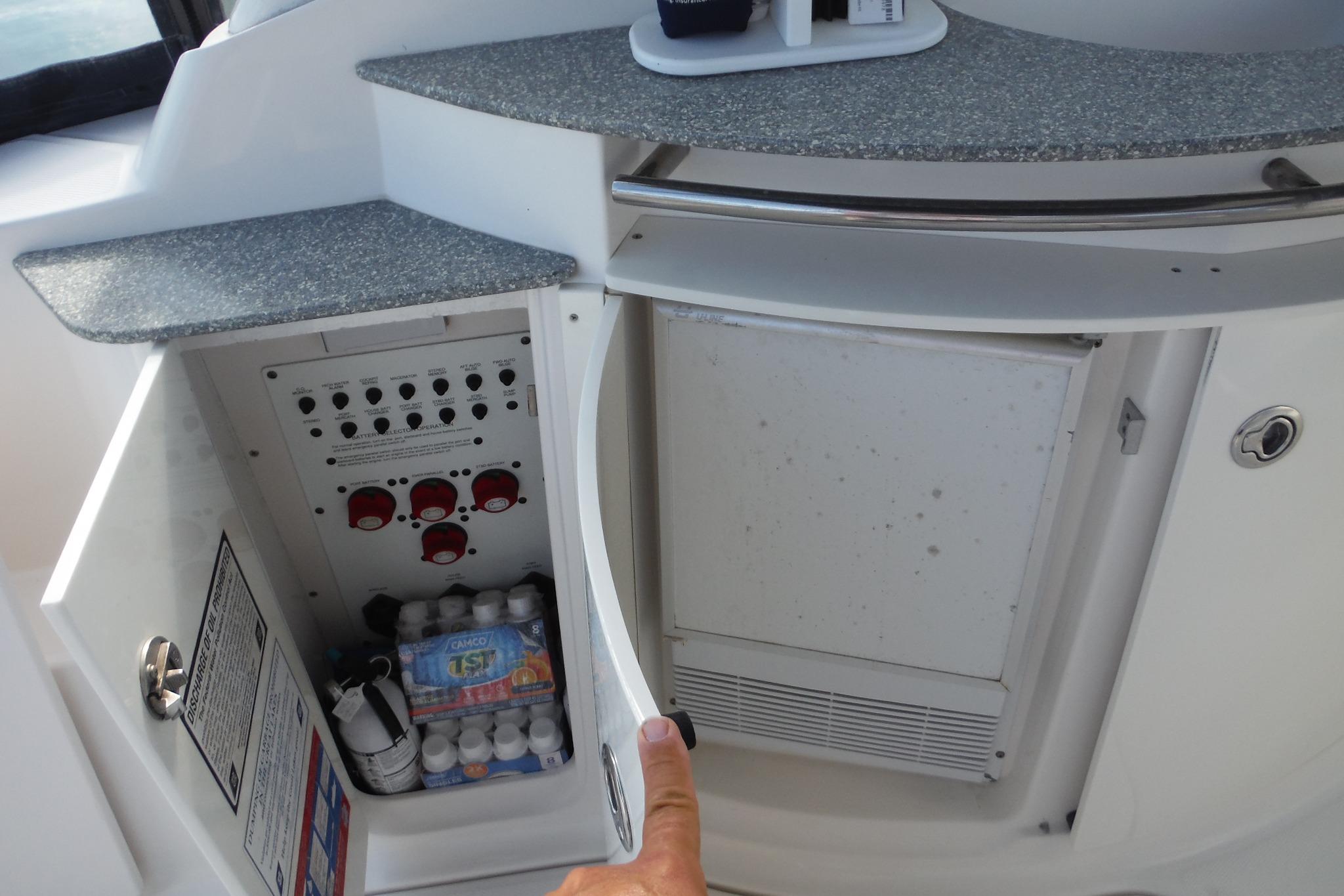 2005 Chaparral Signature 350 yacht interior with open cabinet showing control panel and storage.