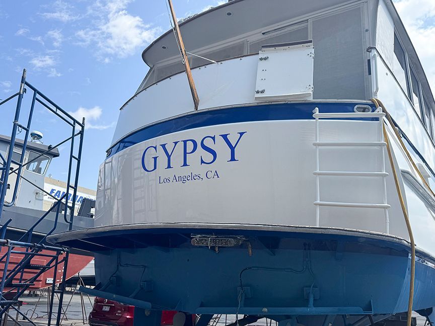 Rear view of a 1961 Burger 63 yacht, on dry dock with blue and white paint.