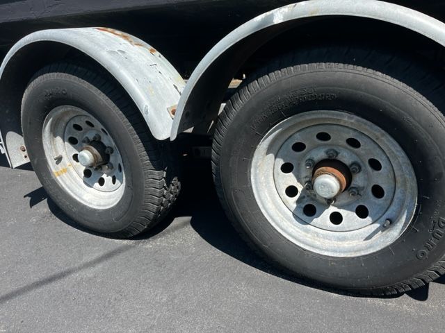 Close-up of a boat trailer with two large tires on asphalt.