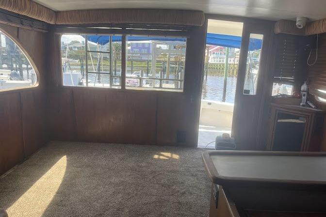 Interior of 1989 Topaz 44 Sportfisherman yacht with carpeted floor and marina view.