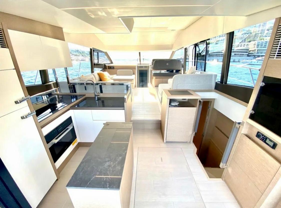 Luxurious interior of 2023 Prestige 520 yacht with modern kitchen and seating area.