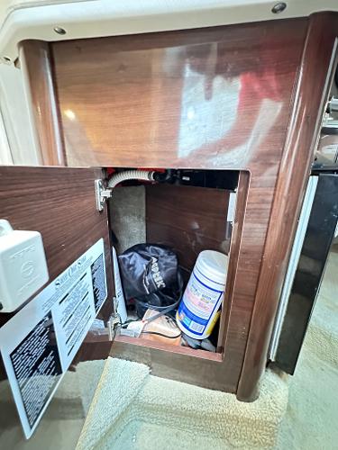 2015 Sea Ray 260 Sundancer interior storage compartment with cleaning supplies and equipment.