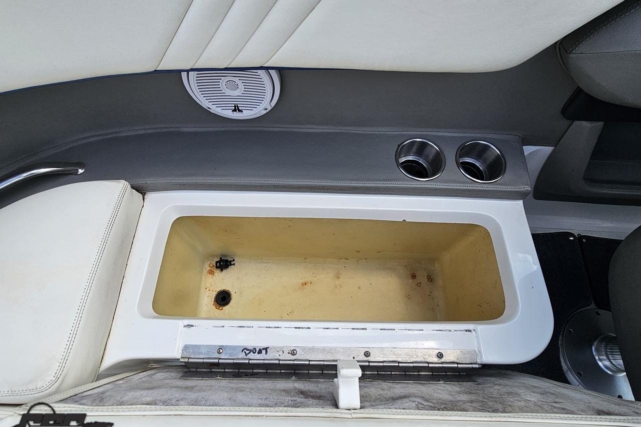 Interior of a 2010 Cobalt 232 WSS boat showing storage compartment and cup holders.