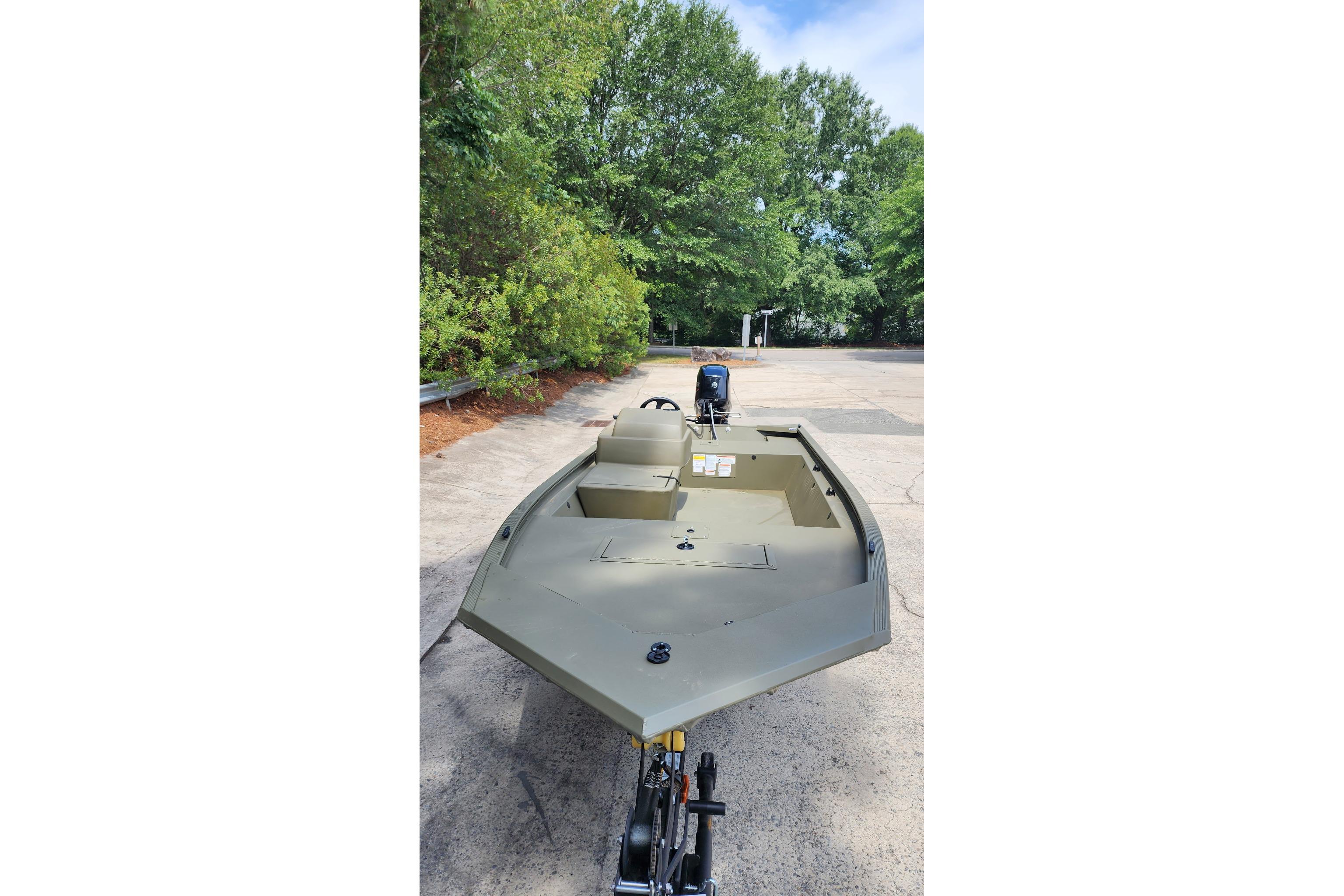 2026 Tracker Grizzly 1648 SC boat on trailer, surrounded by greenery.