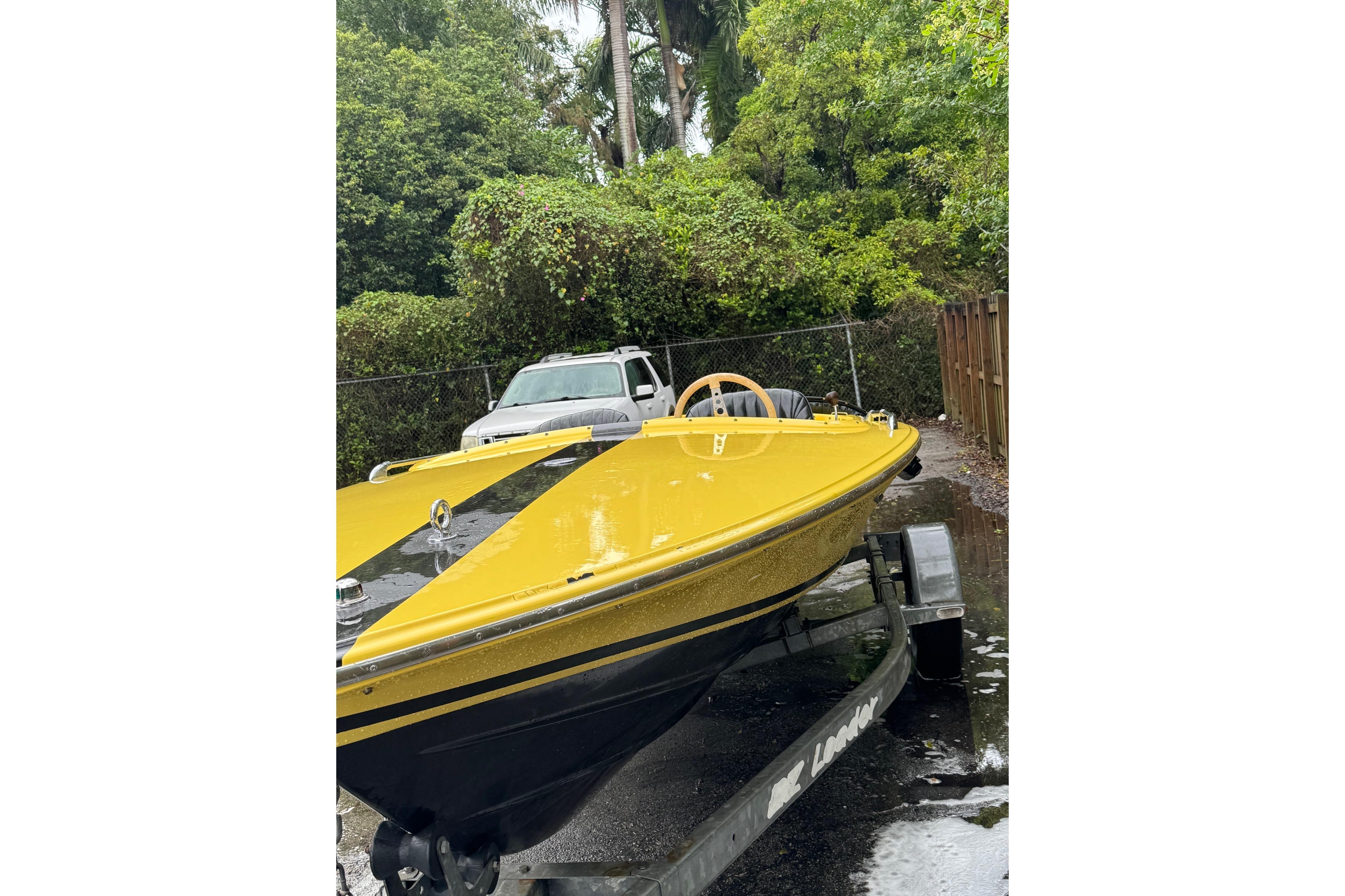Yellow 1987 Donzi 16 Classic boat on trailer, surrounded by greenery.