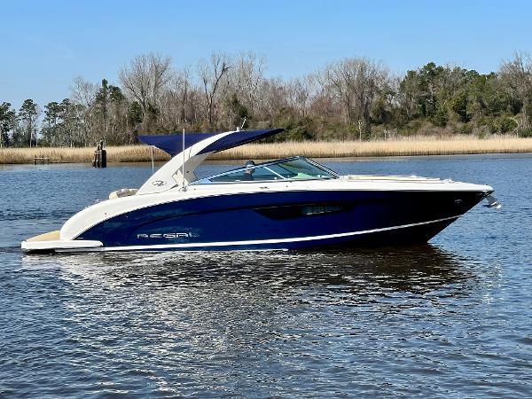 A blue and white 2018 Regal 3300 cruising on calm waters.