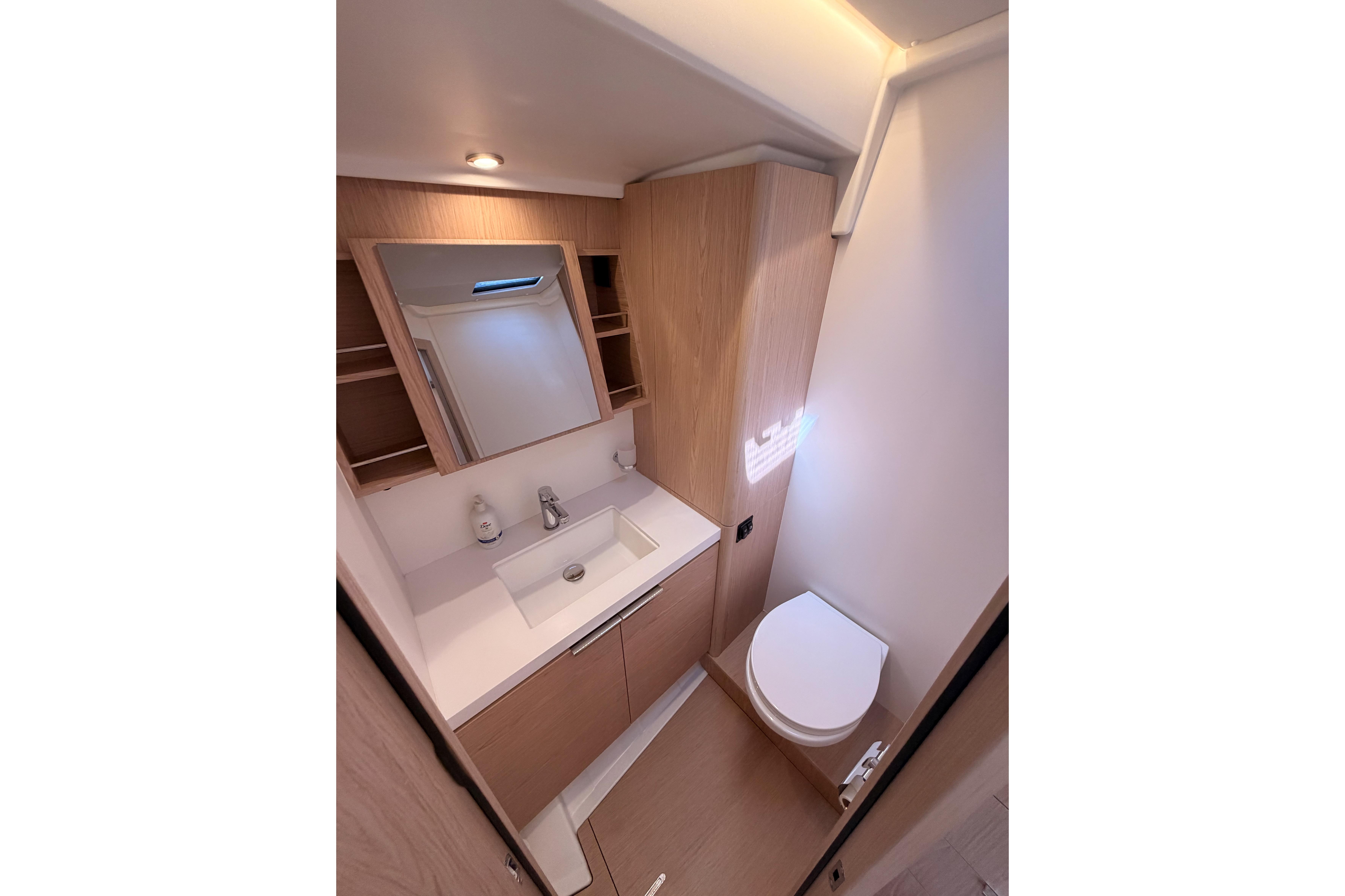 Modern bathroom interior on 2022 Beneteau Oceanis Yacht 54, featuring sleek sink and toilet.