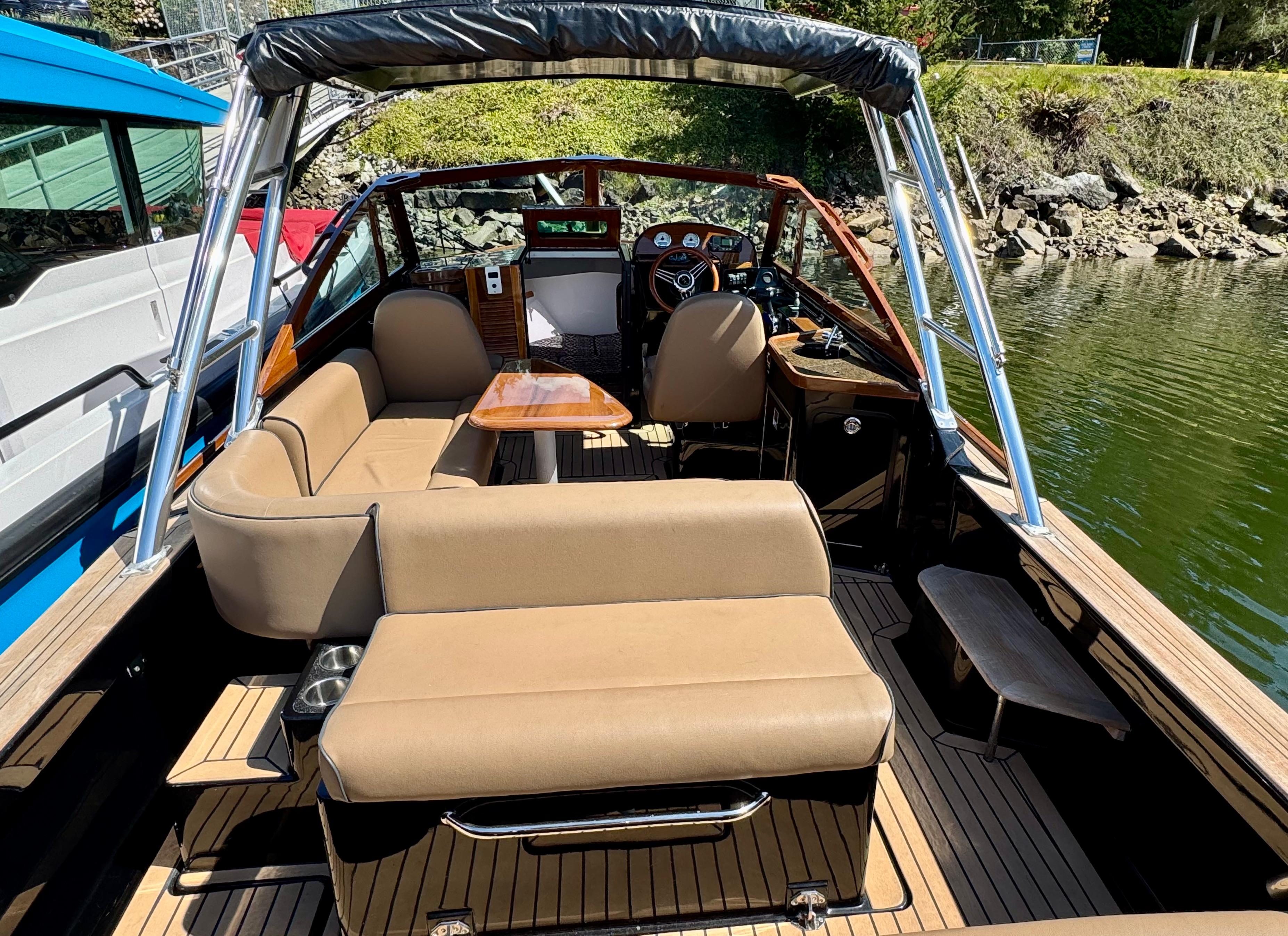 2021 Hunt Yachts Harrier 26 interior with tan seating and wooden accents, docked by the water.