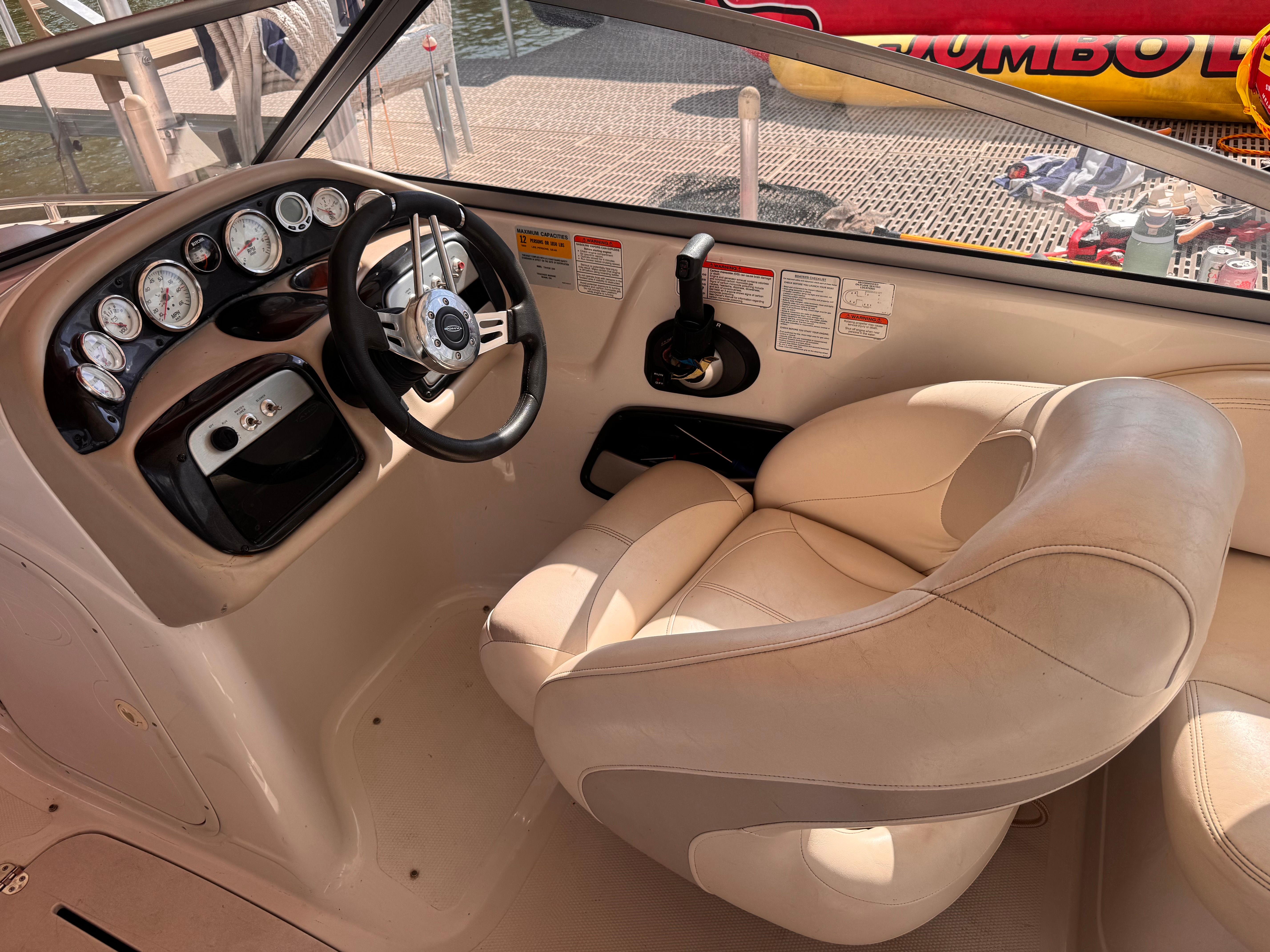 The image shows the cockpit of a 2011 Tahoe 228 with a beige leather seat and dashboard.