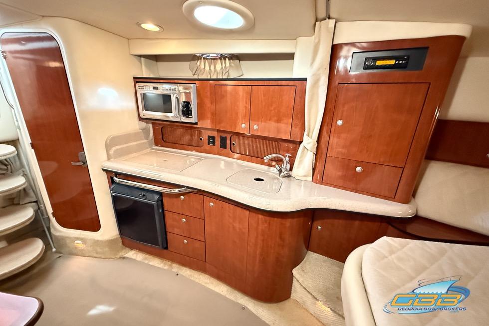 2007 Sea Ray Sundancer 320 interior with kitchenette, featuring wood cabinetry and modern appliances.