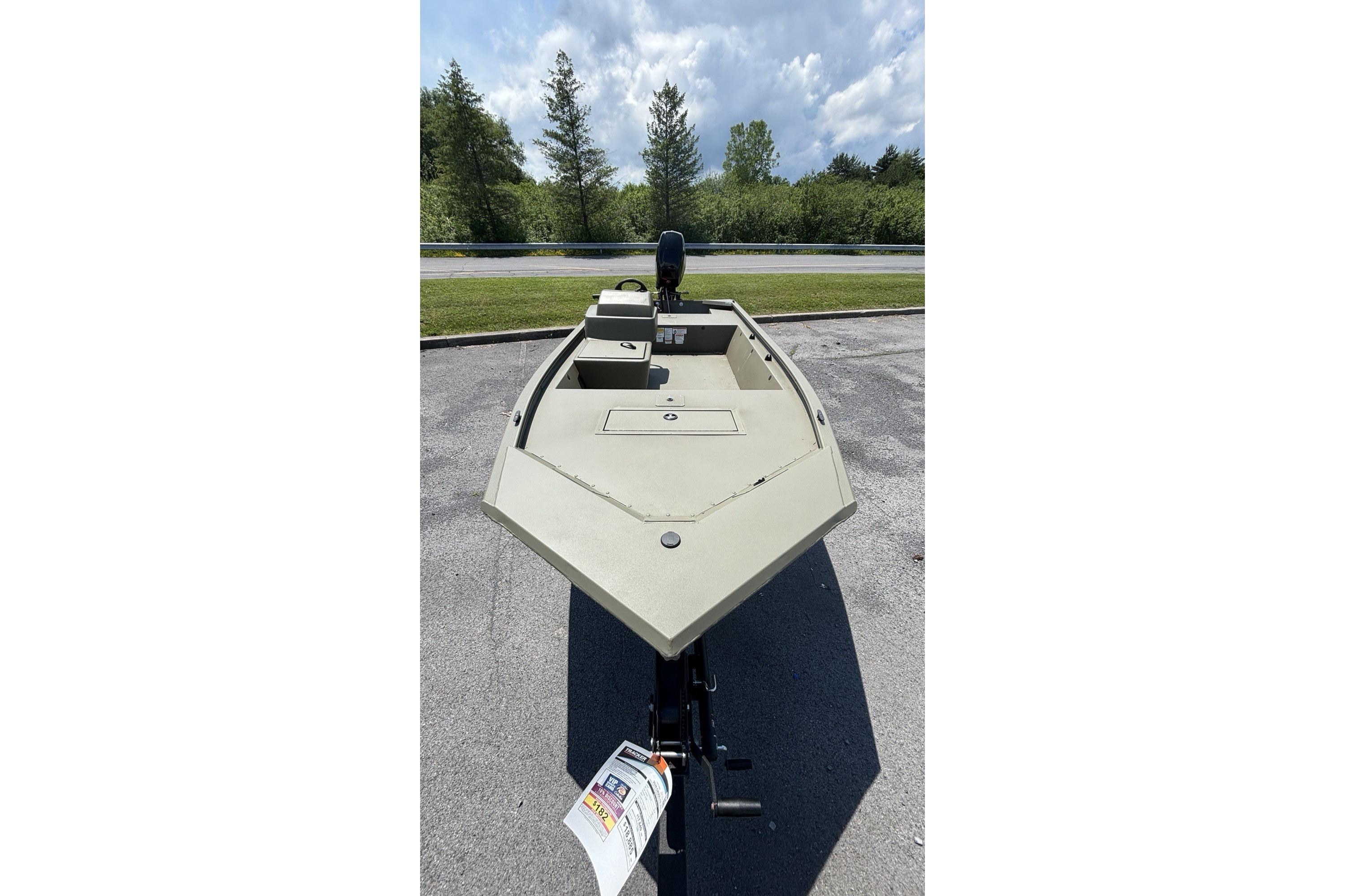 2026 Tracker Grizzly 1648 SC boat on trailer, parked outdoors under cloudy sky.