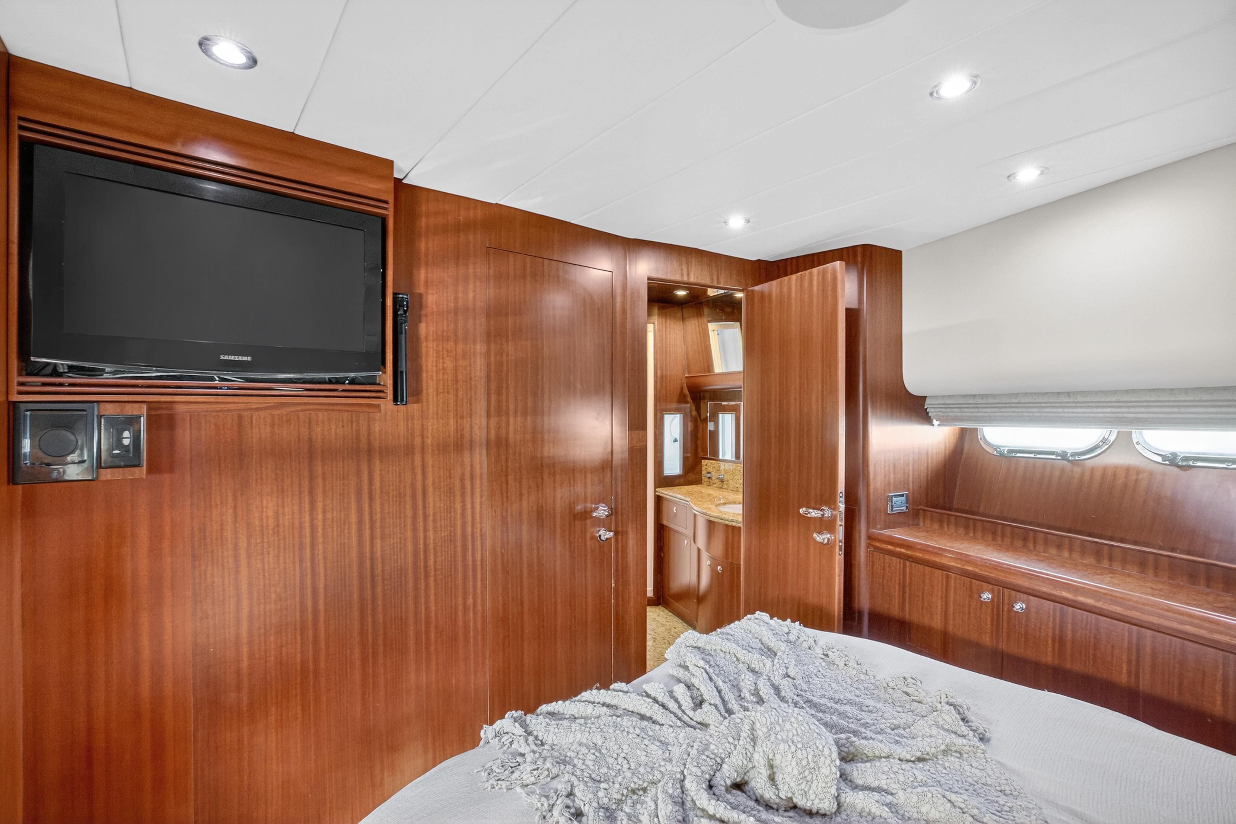 Luxurious 2009 Horizon Flybridge yacht bedroom with wood paneling, TV, and ensuite bathroom.