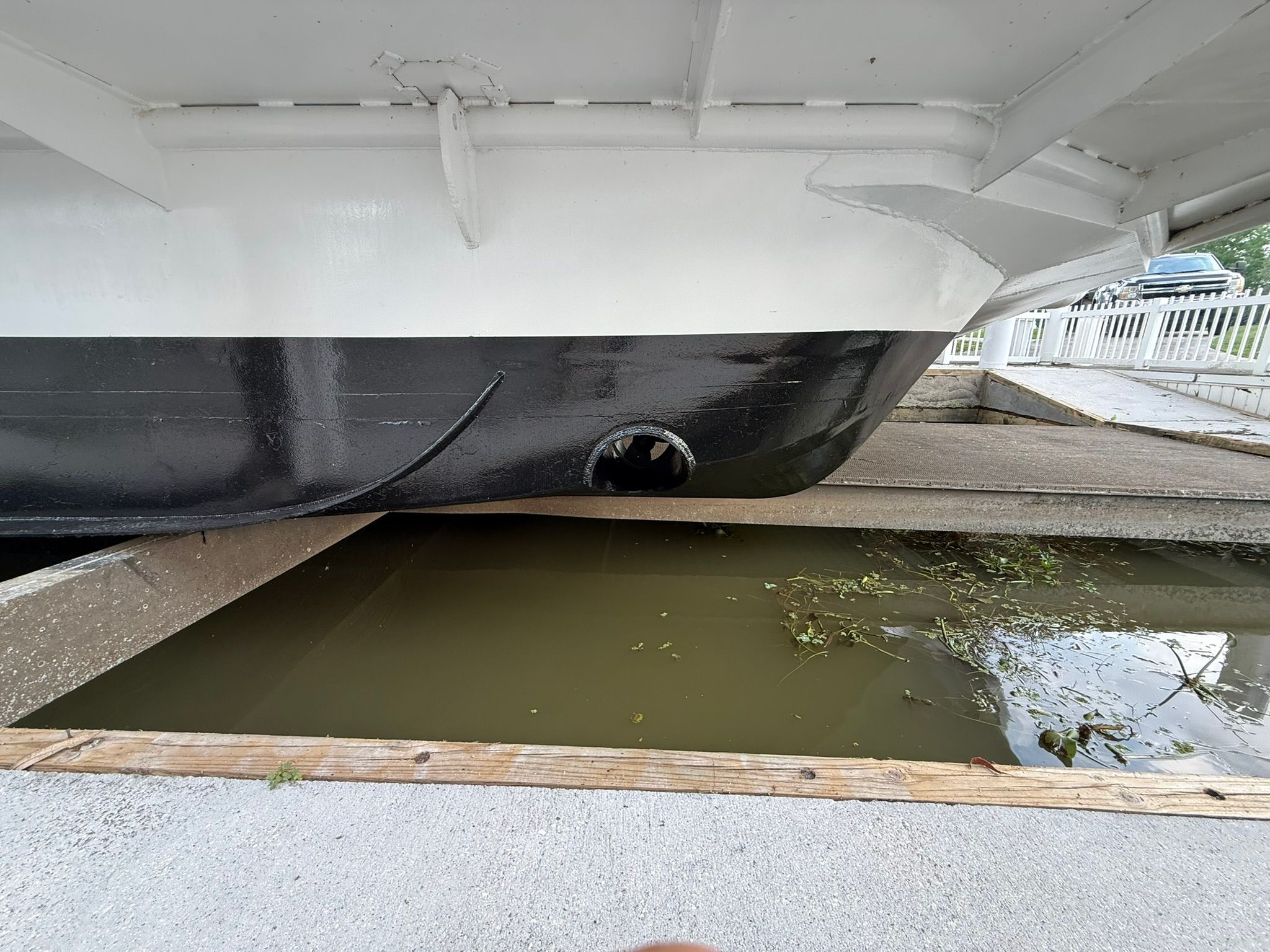 The hull of a boat is partially above water in a dry dock.