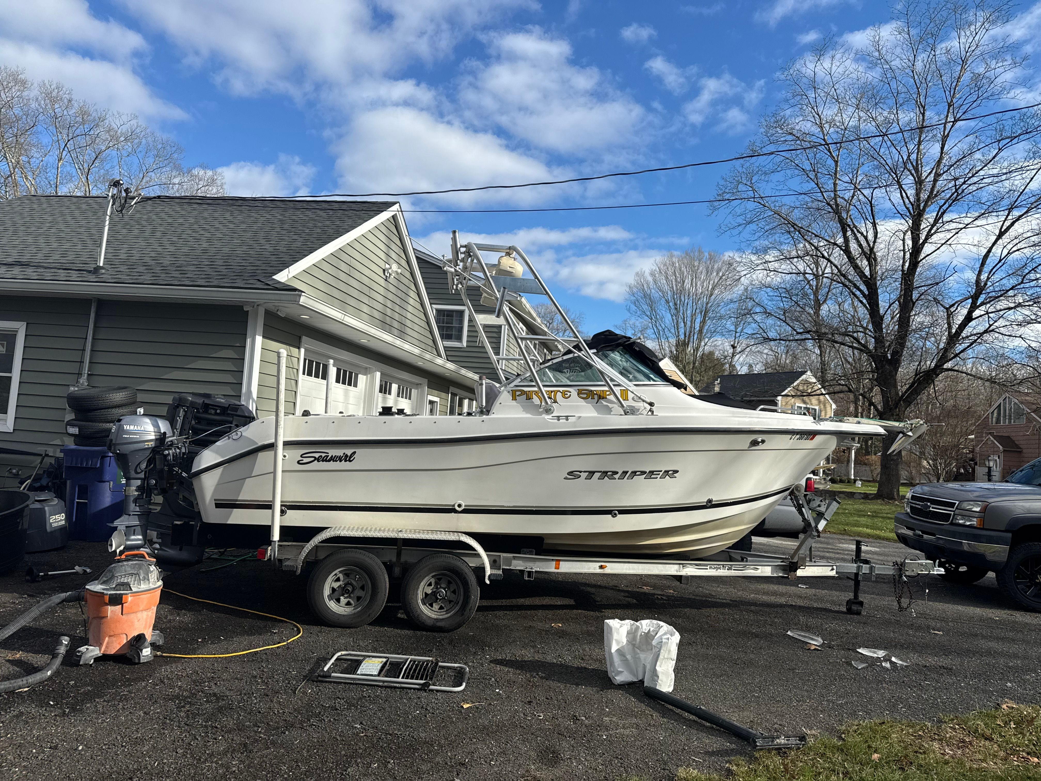 A 2002 Seaswirl Striper 2101 DC on a trailer next to a house.