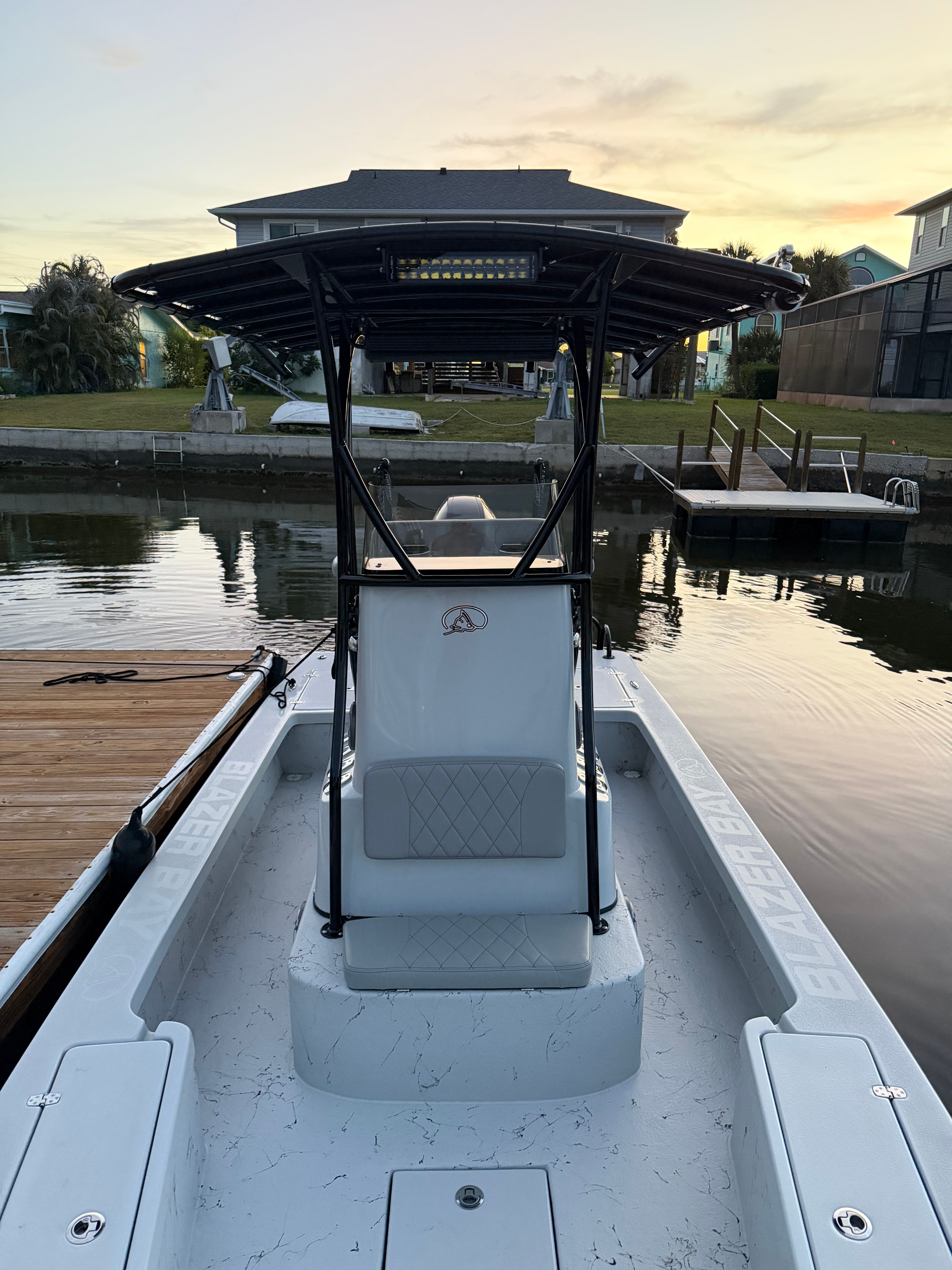 A 2022 Blazer Bay 2420 GTS with T-top, docked at a calm waterway.