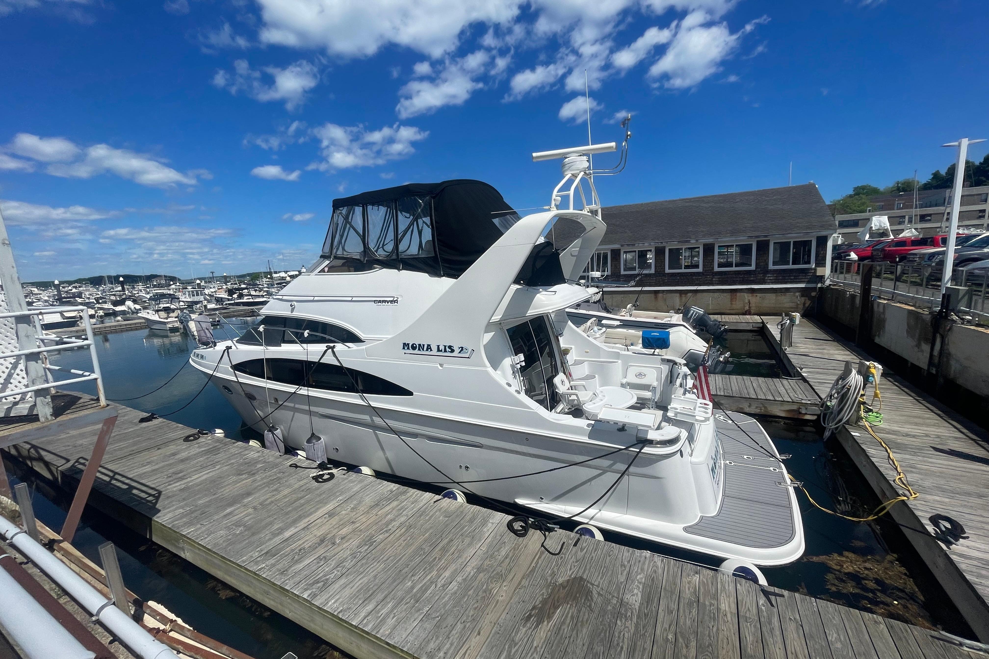 2002 Carver 410 Sport Sedan docked at a marina under a clear blue sky.