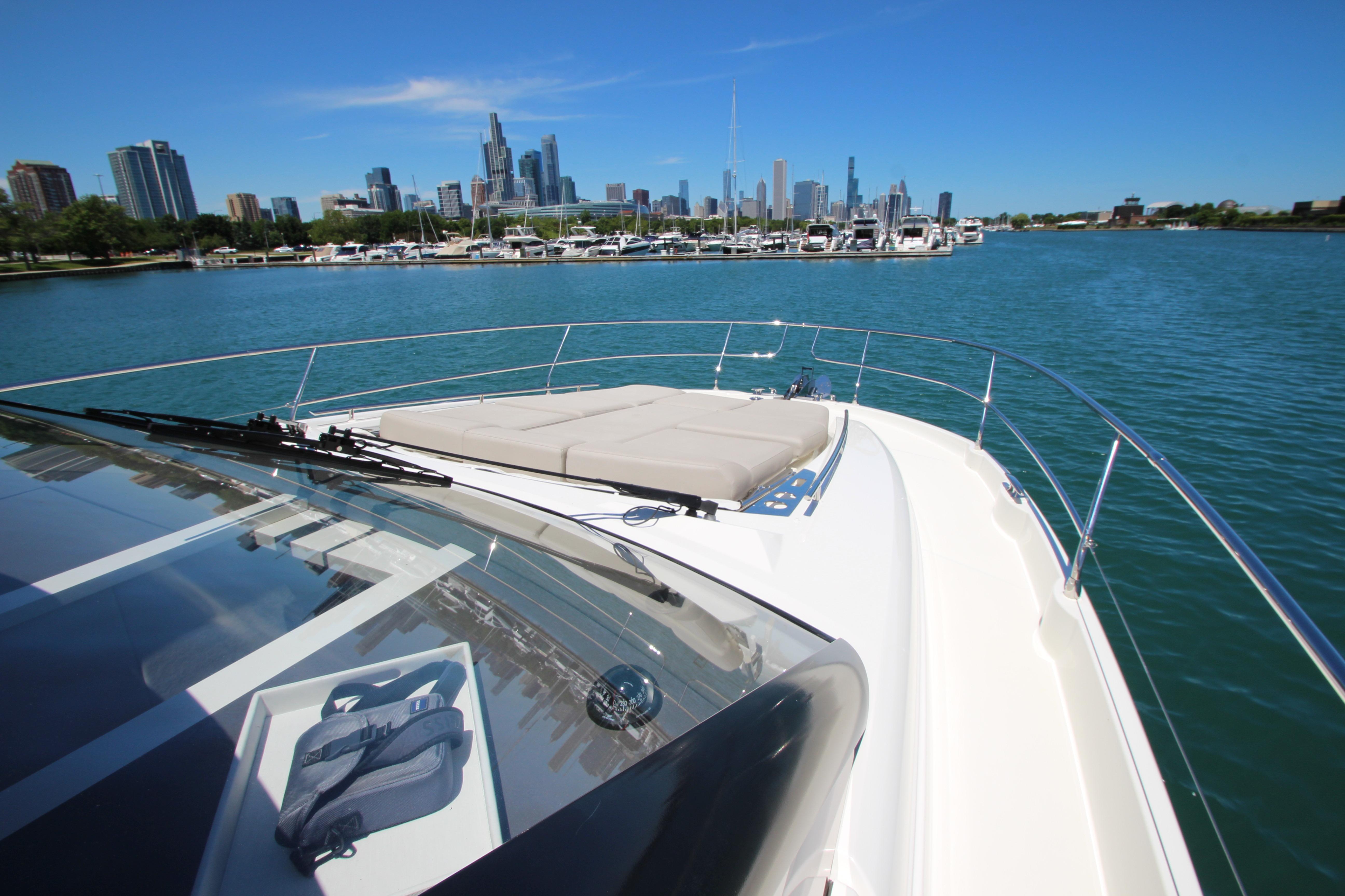 Prestige 520 yacht cruising near city skyline, 2022 model, clear blue sky and water.