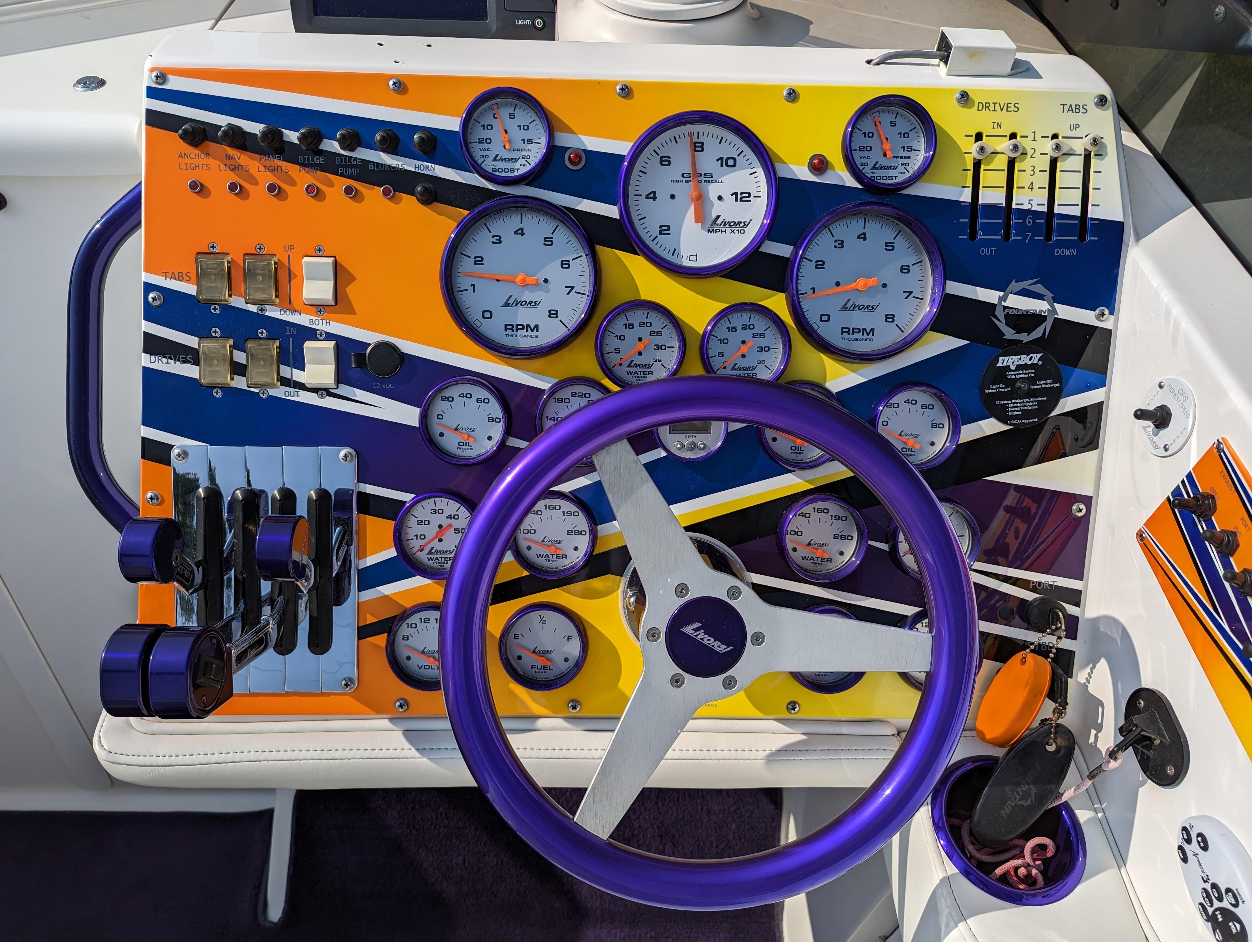 Colorful boat dashboard with gauges and controls, featuring a purple steering wheel. Fountain 42, 2006 model.