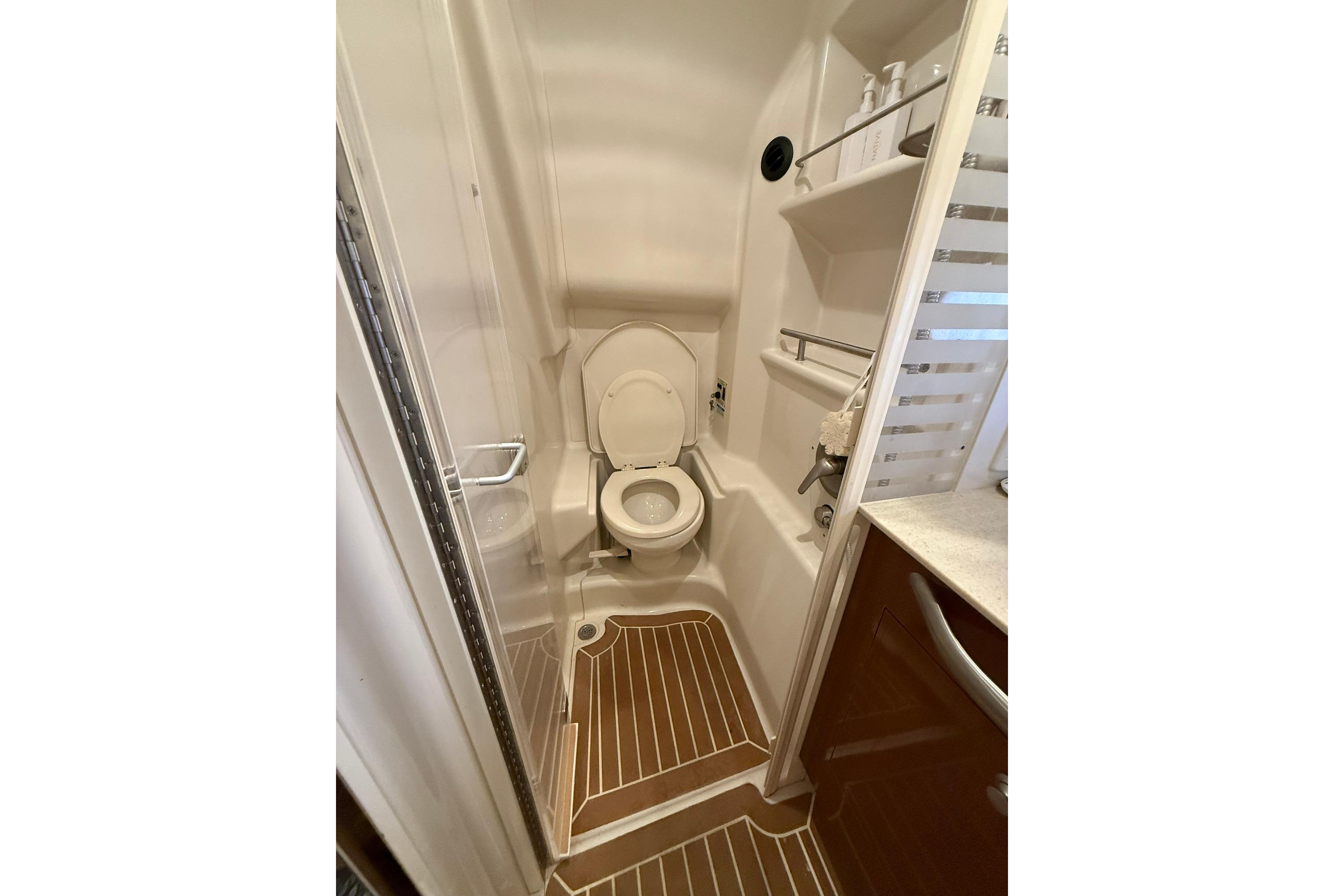 2009 Sea Ray 350 Sundancer bathroom with toilet, shelves, and wooden floor accents.