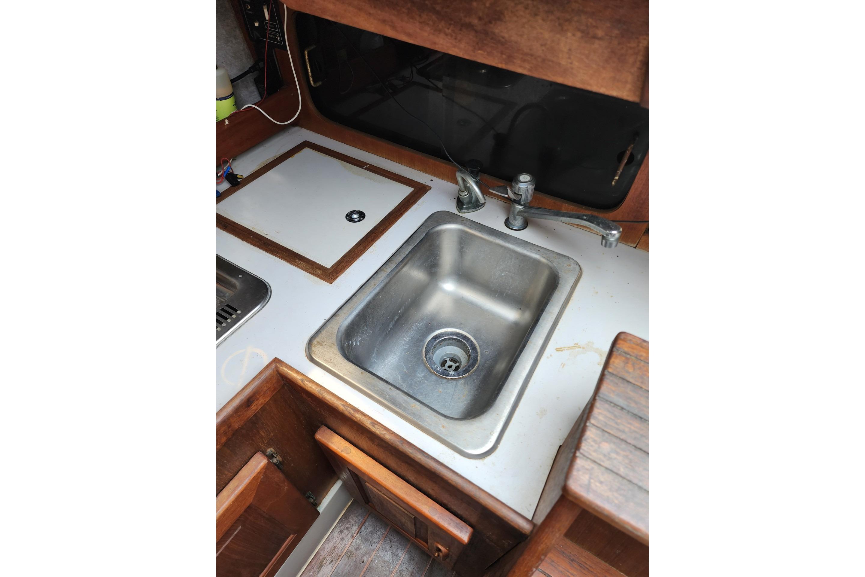 1988 O'Day 272 LE sailboat galley with stainless steel sink and wooden cabinetry.